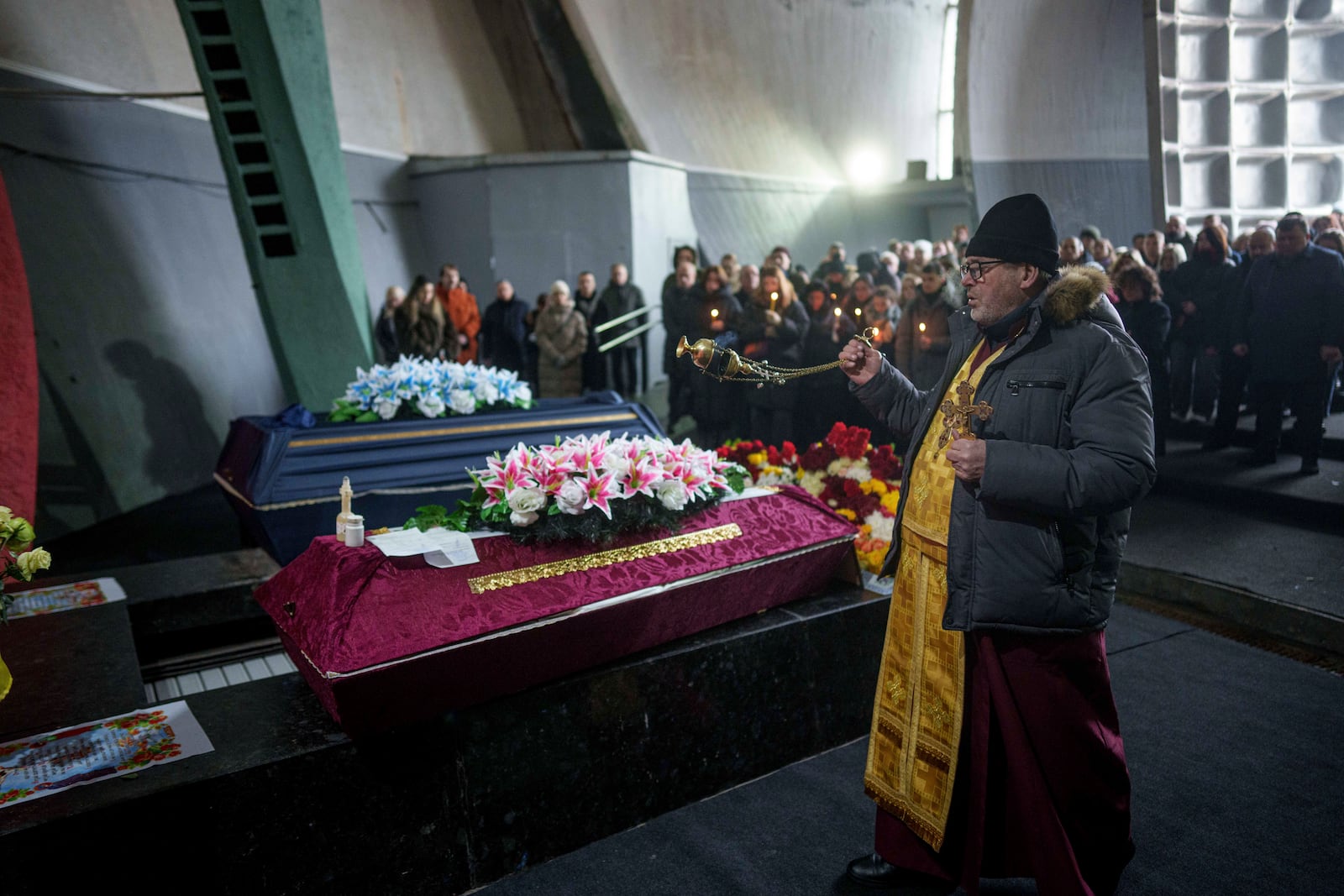 An Orthodox priest performs a funeral service of neurobiologist Ihor Zyma and his wife, biologist Olesia Sokur who were killed by a Russian strike on Jan. 1, in Kyiv, Monday, Jan. 6, 2025. (AP Photo/Evgeniy Maloletka)