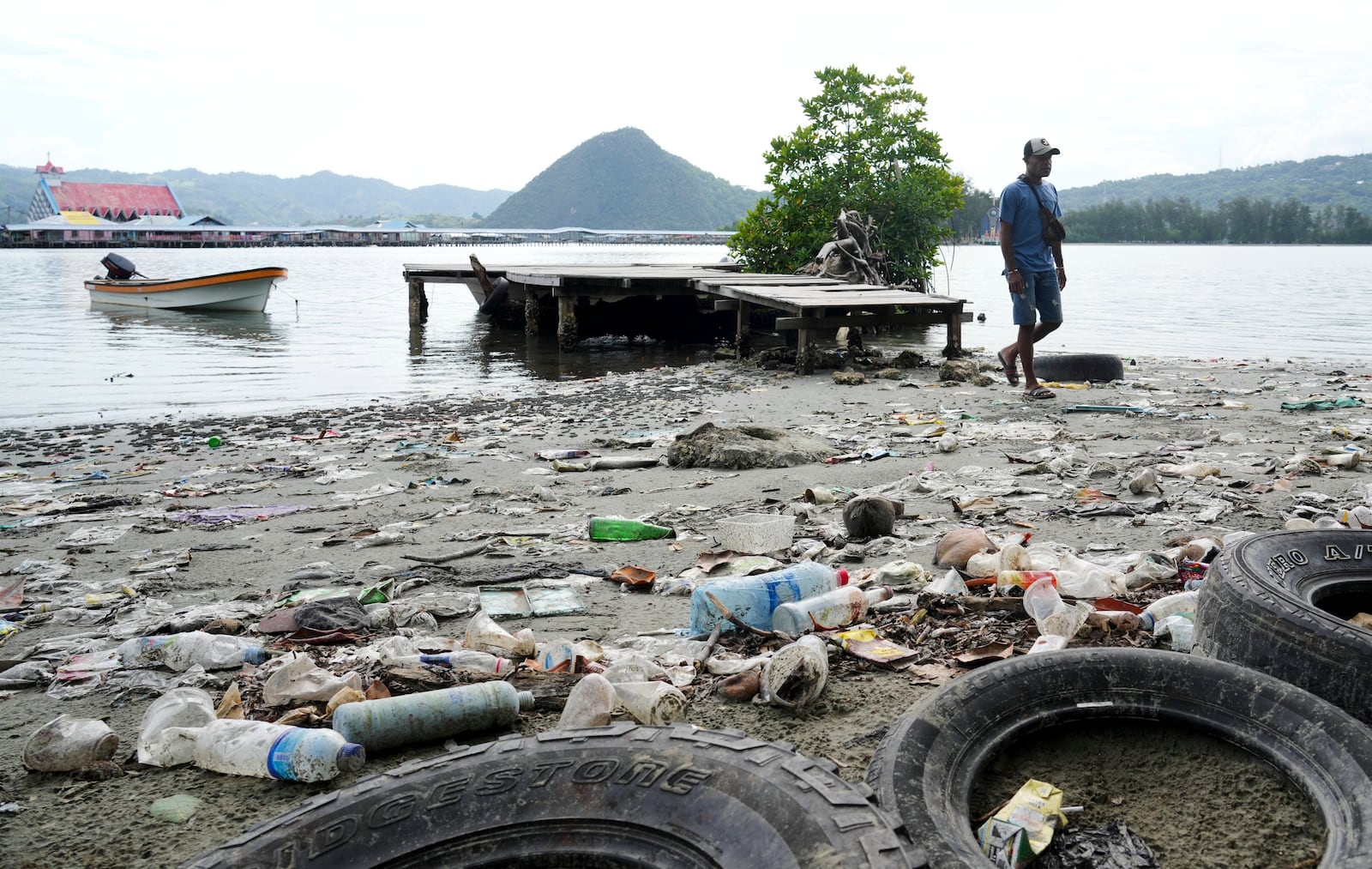 FILE - A man walks past plastic waste strewn along at Enggros village beach in Jayapura, Papua province, Indonesia, Oct. 2, 2024. (AP Photo/Firdia Lisnawati, File)