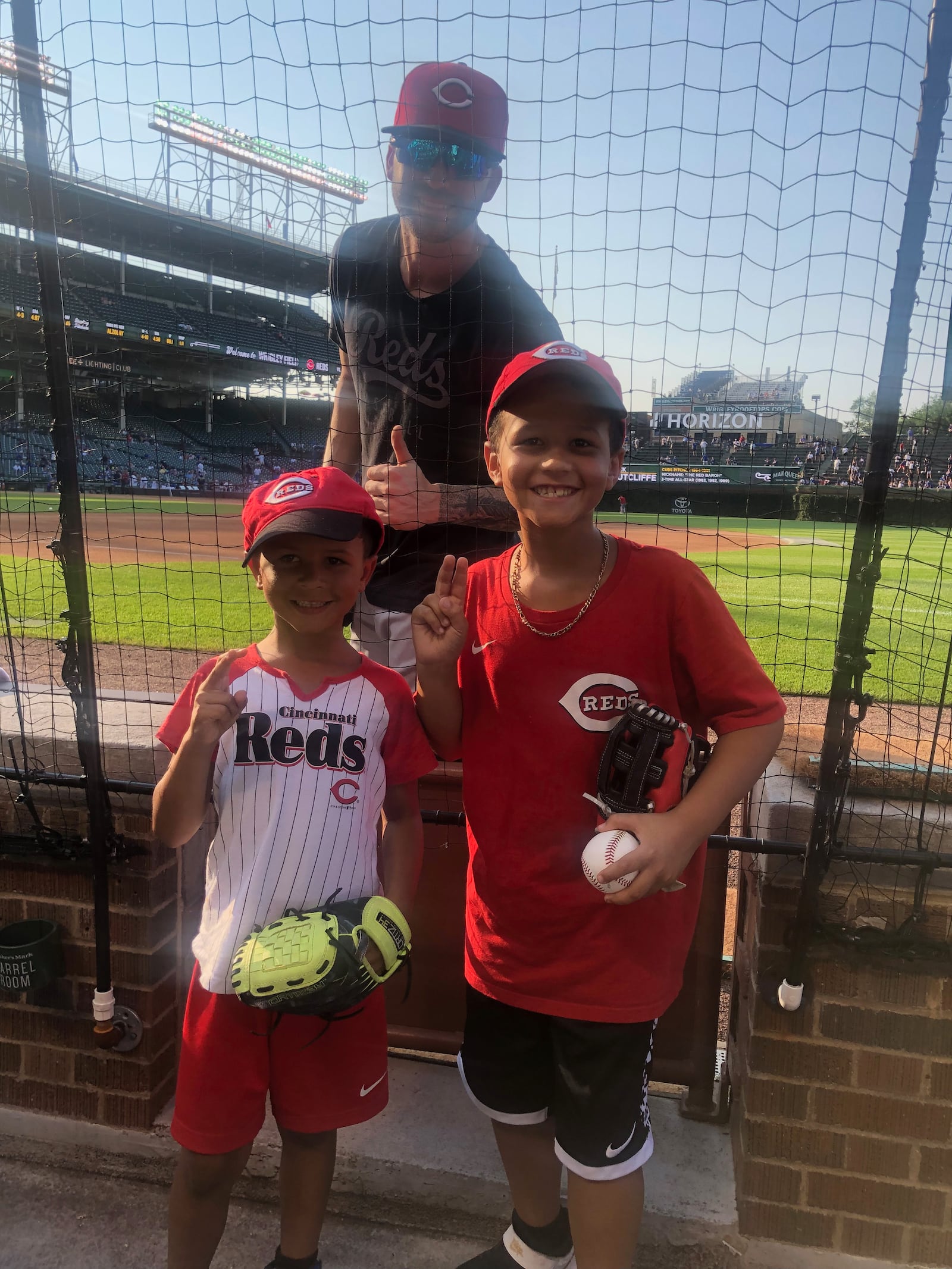 Noah Peterson, left, and Brandon Peterson Jr. are pictured with Tyler Naquin, of the Cincinnati Reds, on Tuesday, July 27, 2021, at Wrigley Field in Chicago.