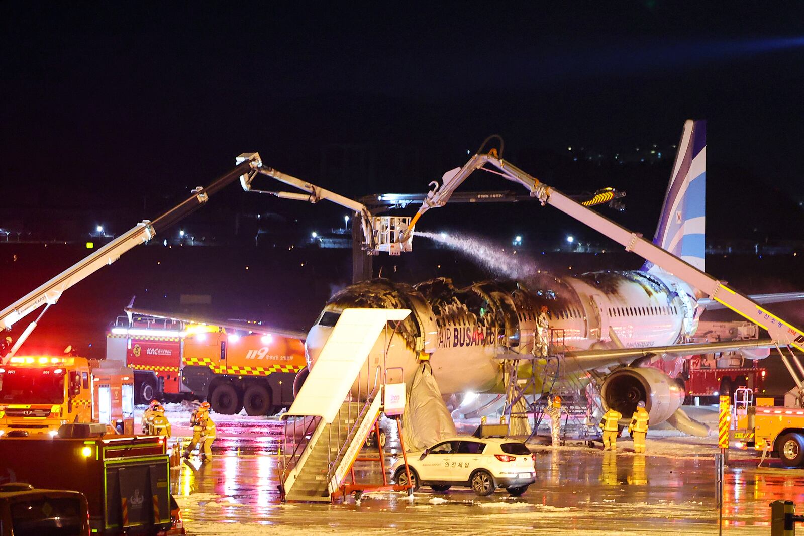 Firefighters work to extinguish a fire on an Air Busan airplane at Gimhae International Airport in Busan, South Korea, Tuesday, Jan. 28, 2025. (Son Hyung-joo/Yonhap via AP)