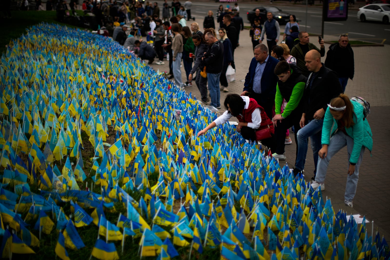 People place Ukrainian flags in memory of civilians killed during the war at Independence Square in central Kyiv, Ukraine, Saturday, Oct. 1, 2022. (AP Photo/Francisco Seco)