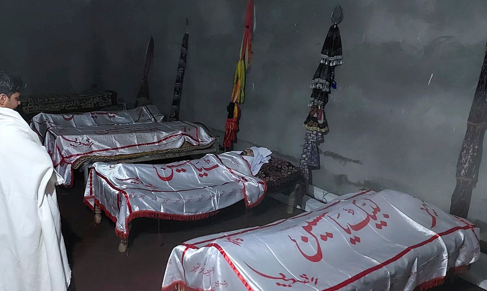 A mourner stands beside the bodies of the victims. who were killed in a gunmen firing incident, before their funeral prayer, in Parachinar, main town of Kurram district of Pakistan's northwestern Khyber Pakhtunkhwa province, Friday, Nov. 22, 2024. (AP Photo/Hussain Ali)