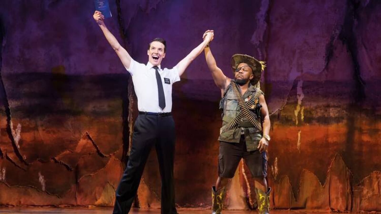 Wright State University musical theater graduate K.J. Hippensteel (left as Elder Price) with Delroy Atkinson (General) in London's West End production of "The Book of Mormon." Hippensteel is currently an ensemble member and understudies the role of Daniel Hillard in the Broadway production of "Mrs. Doubtfire." CONTRIBUTED PHOTO/JOHAN PERSSON