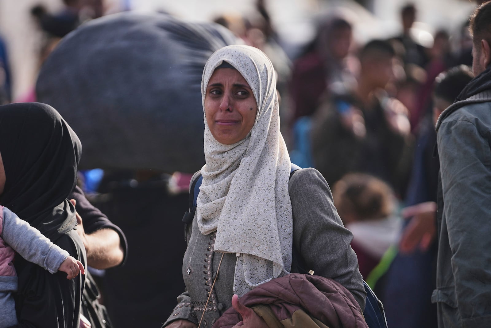 Palestinians wait next to their belongings in central Gaza, Saturday, Jan. 25, 2025, as the Israeli military is warning Palestinians not to return to northern Gaza. (AP Photo/Abdel Kareem Hana)