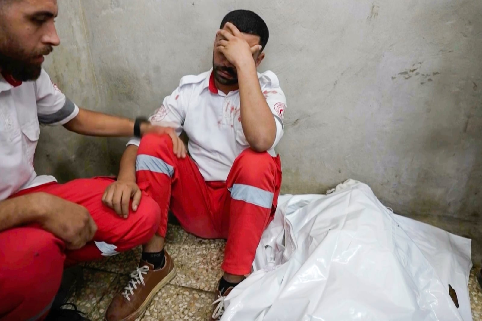 In this image made from an Associated Press video, medic Abed Al Aziz Bardini mourns next to the body of his mother on Wednesday, Oct. 30, 2024, in Deir al-Balah on the Gaza Strip. (AP Photo/Abed Al Kareem Hana)