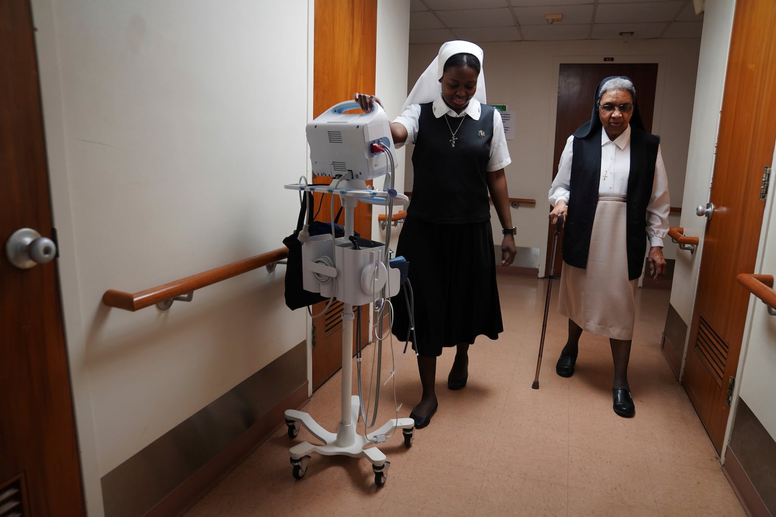 Sister Seyram Mary Adzokpa walks with Sister Mary Laurita in the motherhouse of the Sisters of the Holy Family in New Orleans, Tuesday, June 25, 2024. (AP Photo/Jessie Wardarski) )