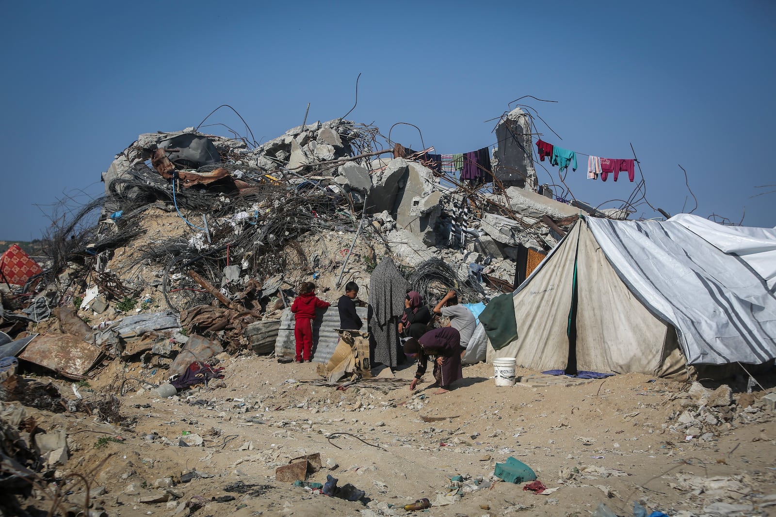 A Palestinian family sits outside a tent next to their destroyed house in Beit Lahia, northern Gaza Strip, Wednesday, Jan. 29, 2025, after Israel began allowing hundreds of thousands of Palestinians to return to the heavily damaged area last Monday. (AP Photo/Jehaid Alshrafi)