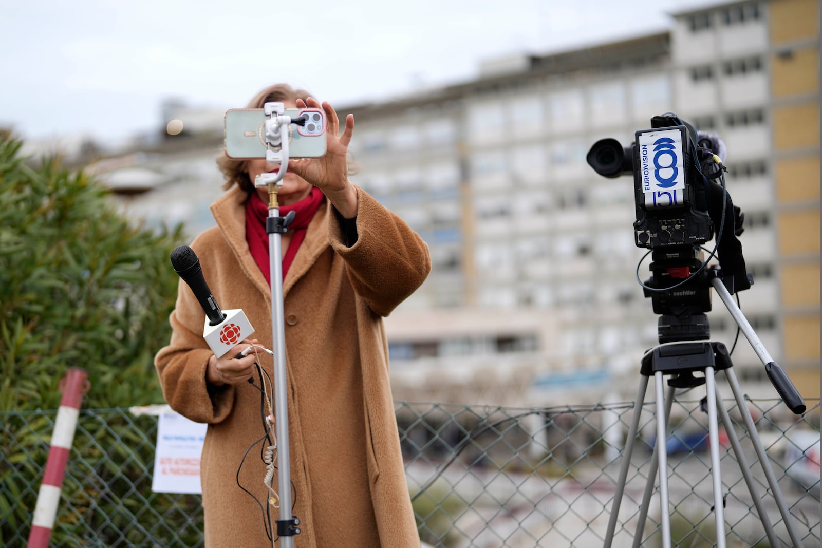 A journalist prepares for her report outside the Agostino Gemelli Polyclinic in Rome, Monday, Feb. 17, 2025, where Pope Francis was hospitalized Friday, Feb. 14, after a weeklong bout of bronchitis worsened and is receiving drug therapy for a respiratory tract infection. (AP Photo/Gregorio Borgia)