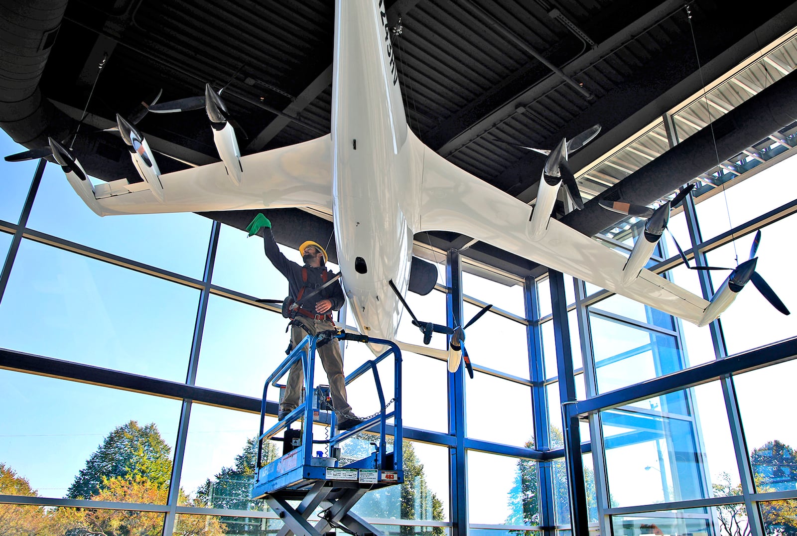 Owen Flannery, an employee with the City of Springfield, cleans the electric vertical take off and landing aircraft that hangs in the lobby of the new National Advanced Air Mobility Center of Excellence at Springfield-Beckley Municipal Airport Thursday, Sept. 14, 2023. BILL LACKEY/STAFF