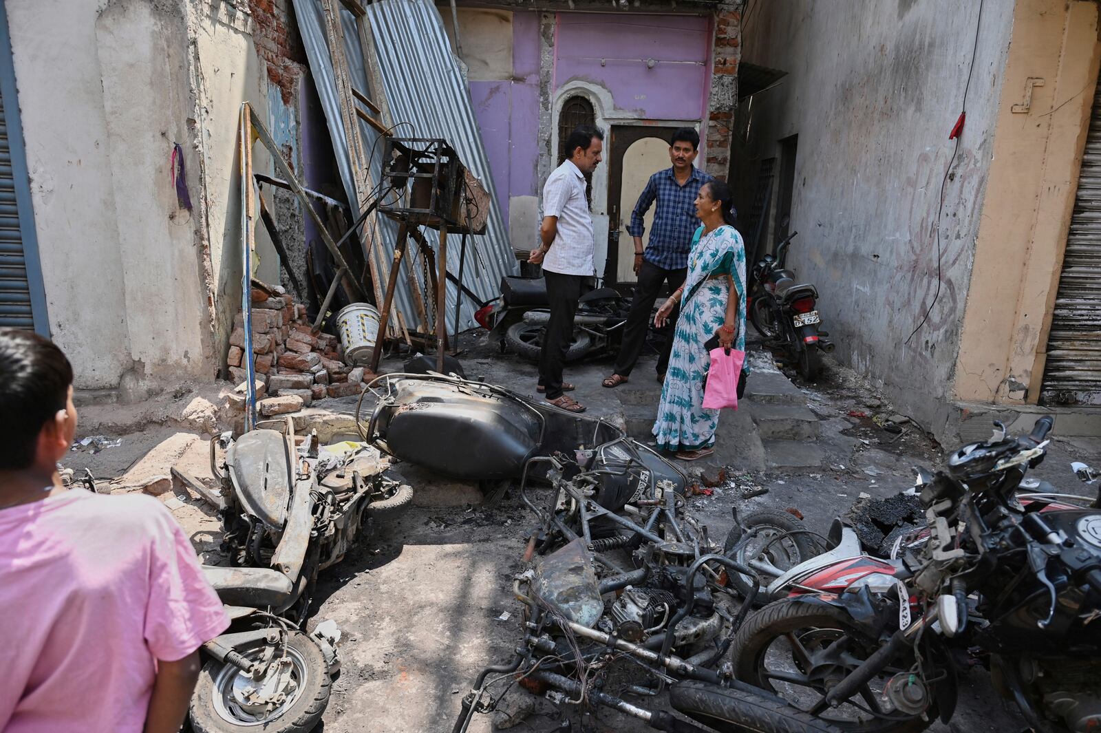 Residents stand next to burnt vehicles a day after communal clashes sparked by protests demanding removal of the tomb of 17th-century Muslim Mughal ruler Aurangzeb in Nagpur, India, Tuesday, March 18, 2025. (AP Photo)