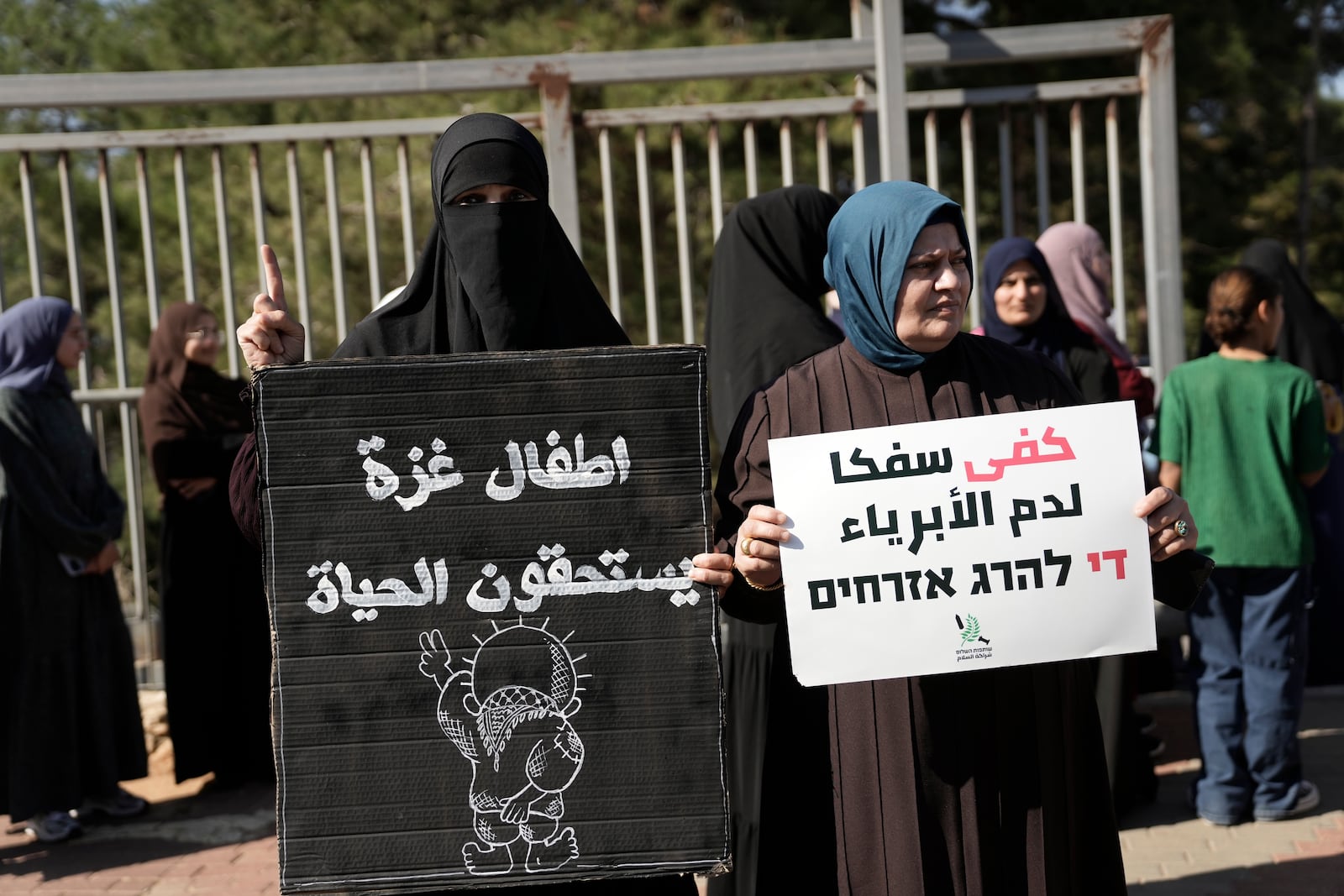 Women hold Arabic placards that read, "Gaza children deserve life," left, and "stop shedding innocent blood," as Palestinian citizens of Israel march against Israel's military operations in the Gaza Strip, in Umm al-Fahm, Israel, Friday, Nov. 15, 2024. (AP Photo/Mahmoud Illean)