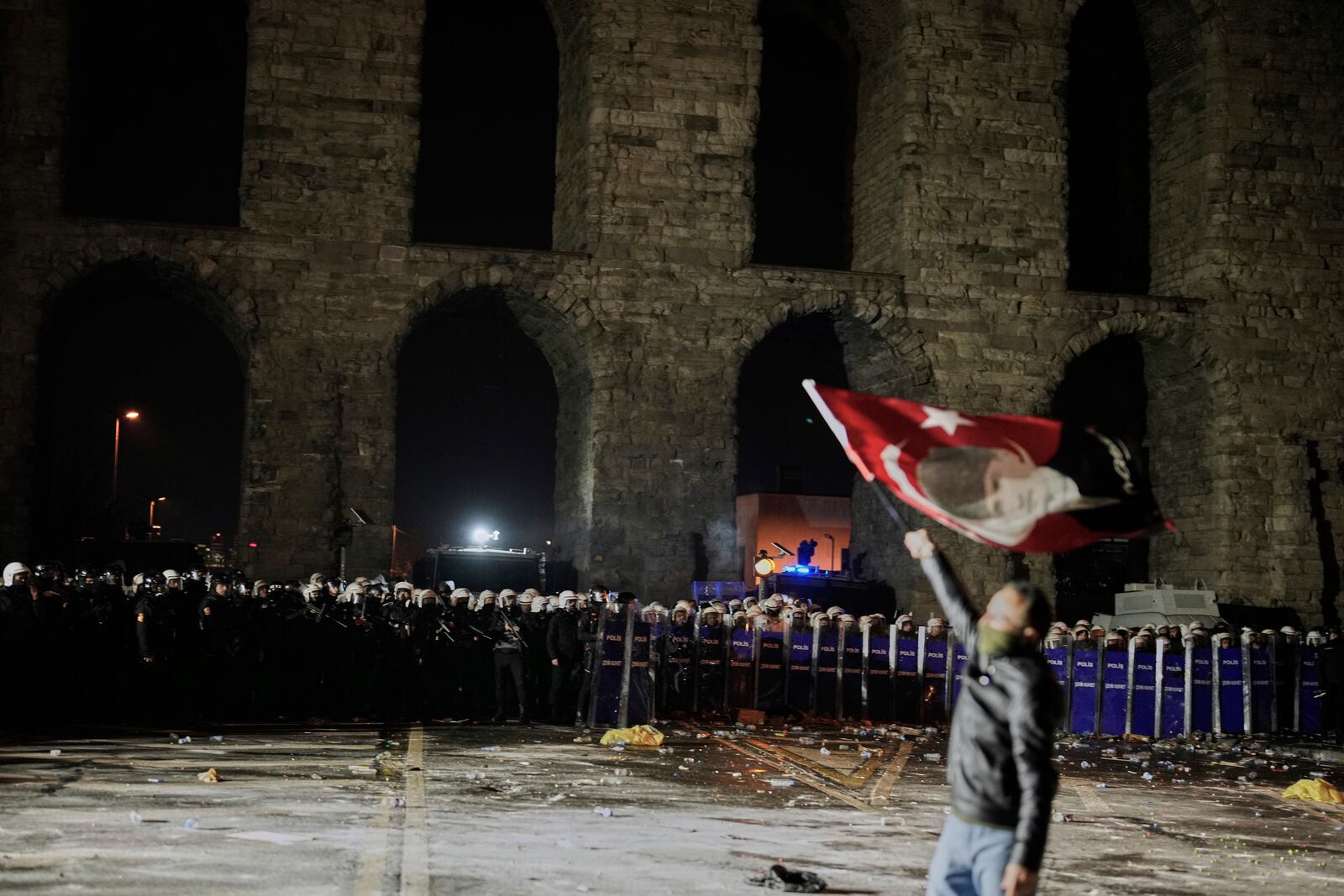 A man holds a Turkish flag with the image of Turkey's founding father Mustafa Kemal Ataturk in front of anti riot police officers during a protest against the arrest of Istanbul's Mayor Ekrem Imamoglu in Istanbul, Turkey, Friday, March 21, 2025. (AP Photo/Emrah Gurel)