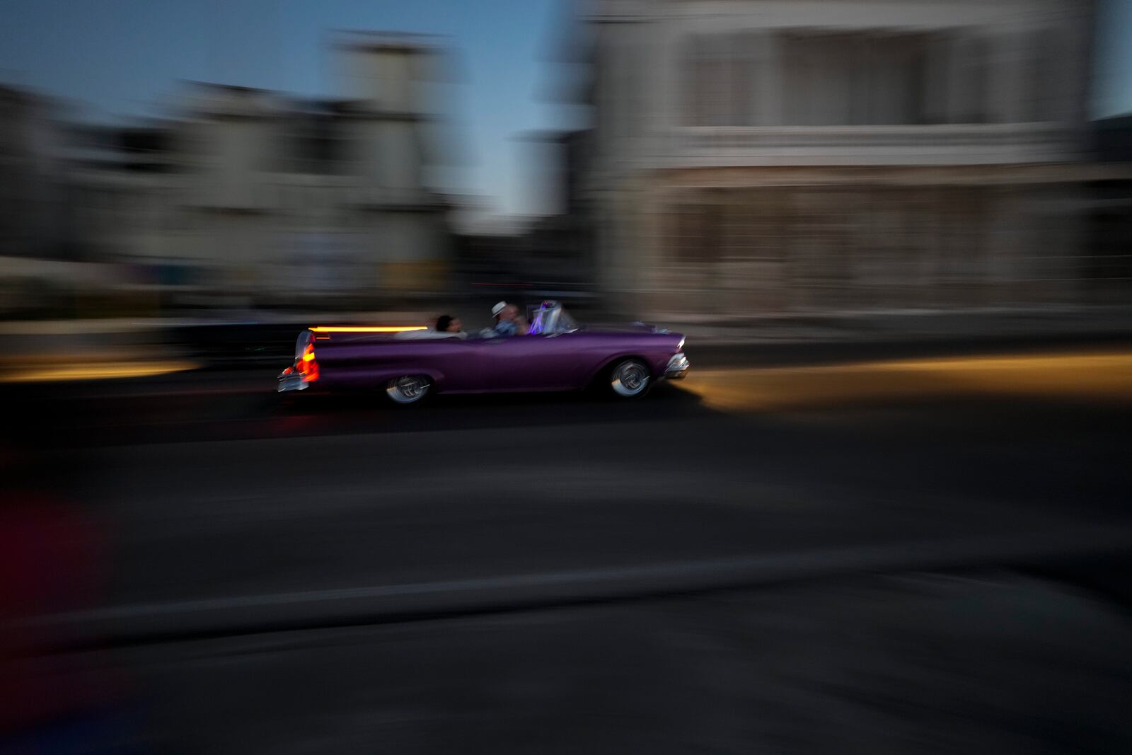 A classic American car with tourists is driven at sunset along the Malecon during a general blackout in Havana, Saturday, March 15, 2025. (AP Photo/Ramon Espinosa)