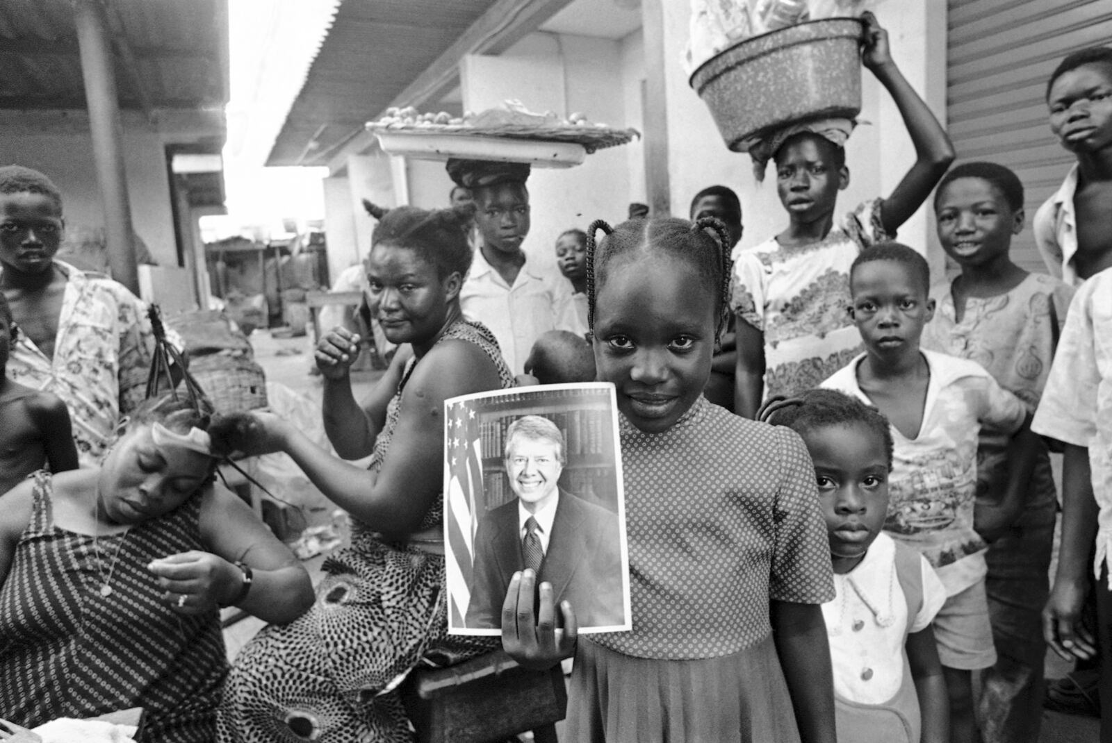 FILE - A girl holds a portrait of U.S. President Jimmy Carter in a market in Lagos, Nigeria, on March 31, 1978, the day of his arrival for a state visit. (AP Photo/Dieter Endlicher, File)