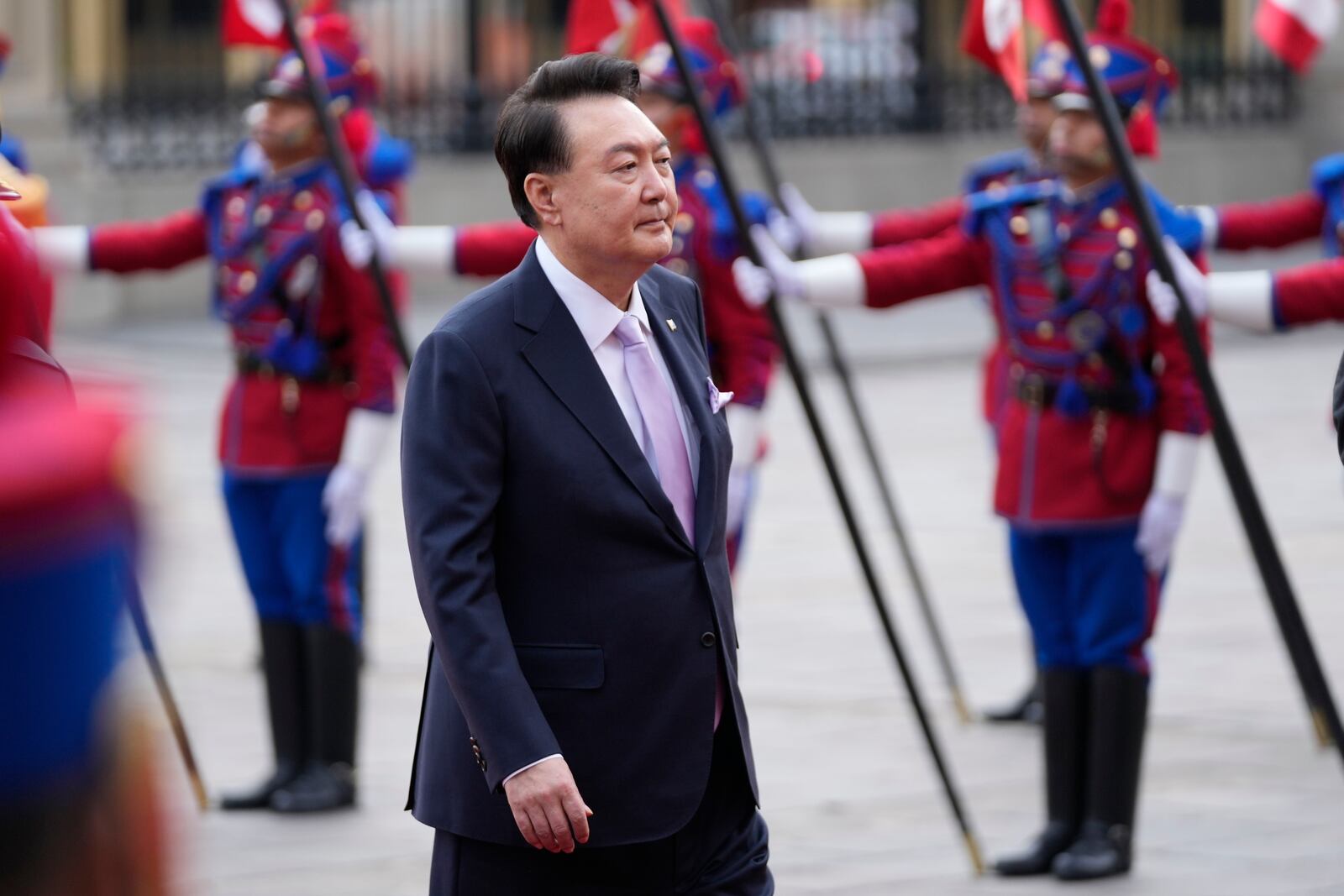 South Korea's President Yoon Suk Yeol walks past an honor guard during a welcoming ceremony at the government palace in Lima, Peru, Saturday, Nov. 16, 2024, following the closing of the Asia-Pacific Economic Cooperation (APEC) summit. (AP Photo/Fernando Vergara)