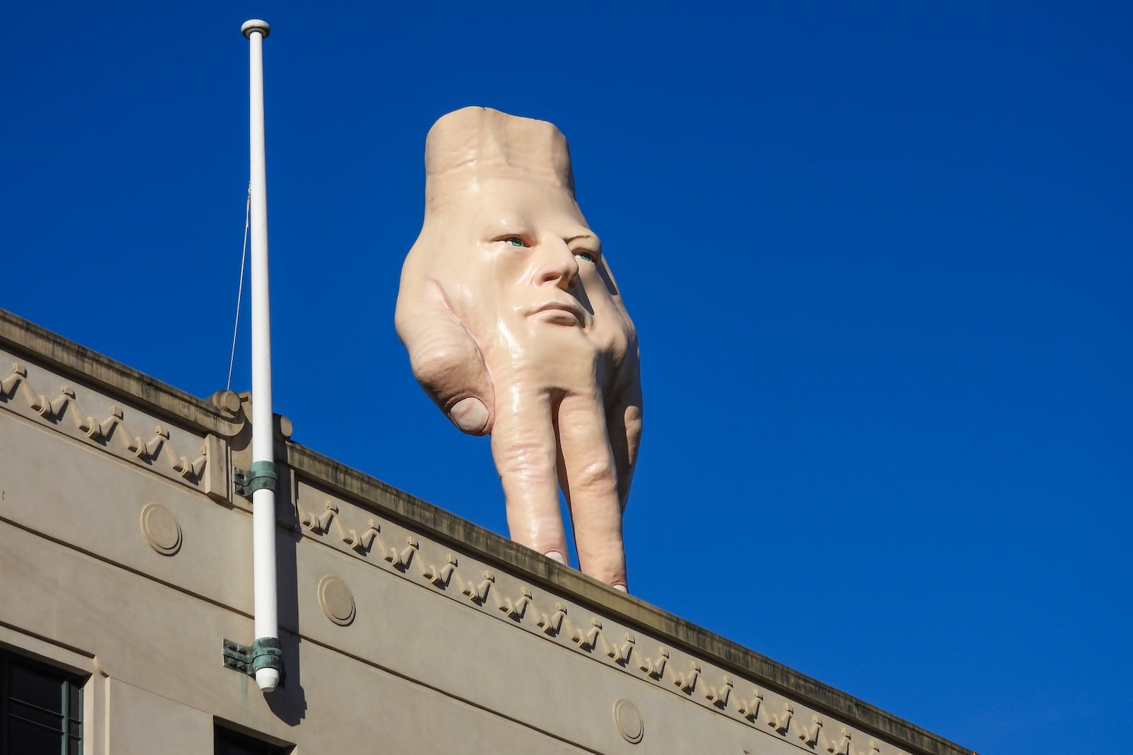 A 16-foot- ( almost 5 meters ) tall hand sculpture named Quasi stands perched on its fingertips atop the roof of an art gallery in Wellington, New Zealand, Wednesday, Oct. 30, 2024. (AP photo/Charlotte Graham-McLay)