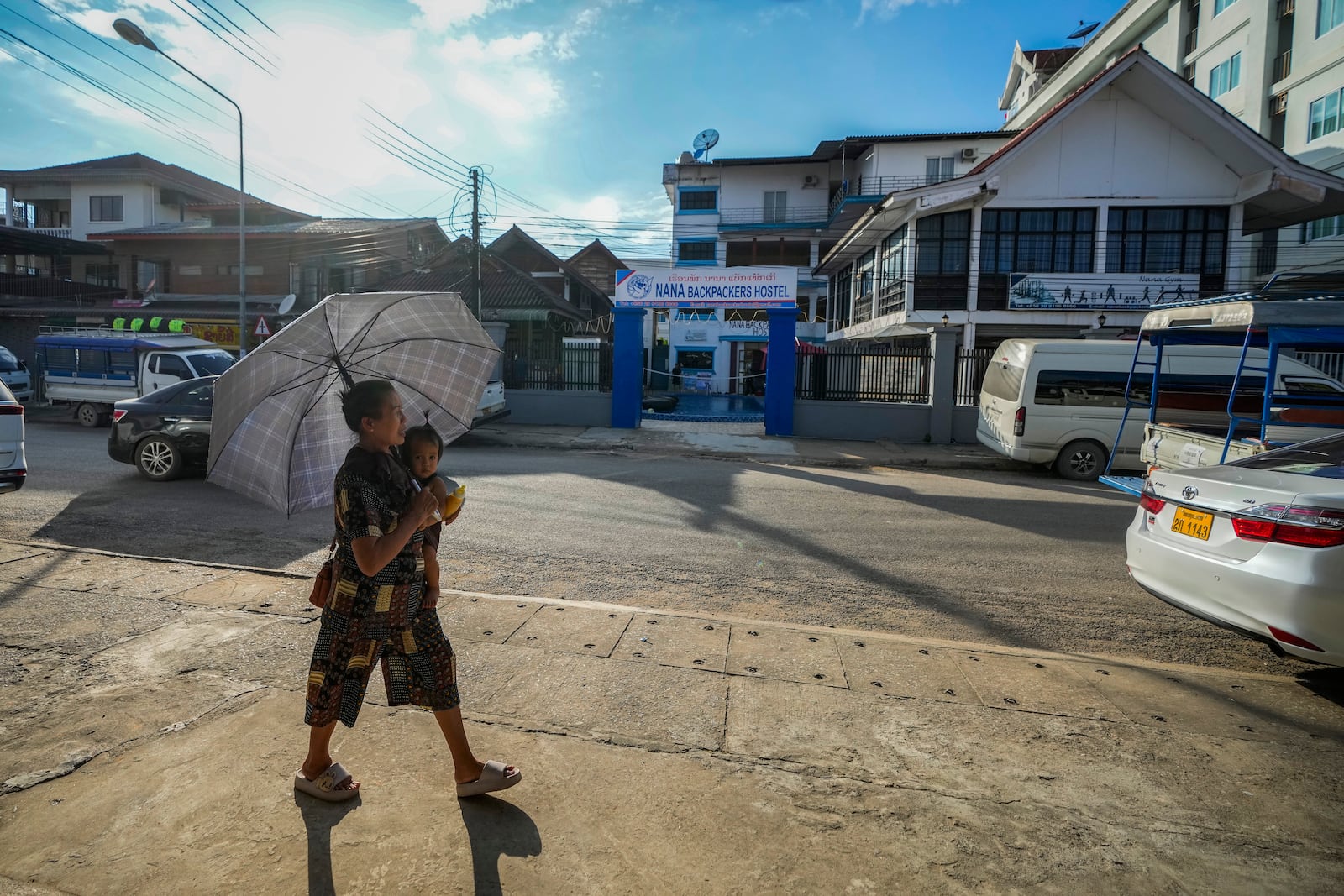 A woman carries a baby as she walks by the Nana Backpack hostel in Vang Vieng, Laos, Tuesday, Nov. 19, 2024. (AP Photo/Anupam Nath)