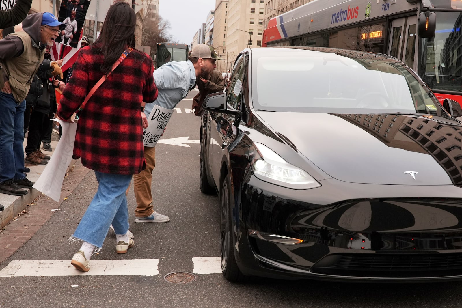 Demonstrators shout at a driver of a Tesla as they protest against the Trump administration near the White House Friday, March 14, 2025, in Washington. (AP Photo/Jacquelyn Martin)