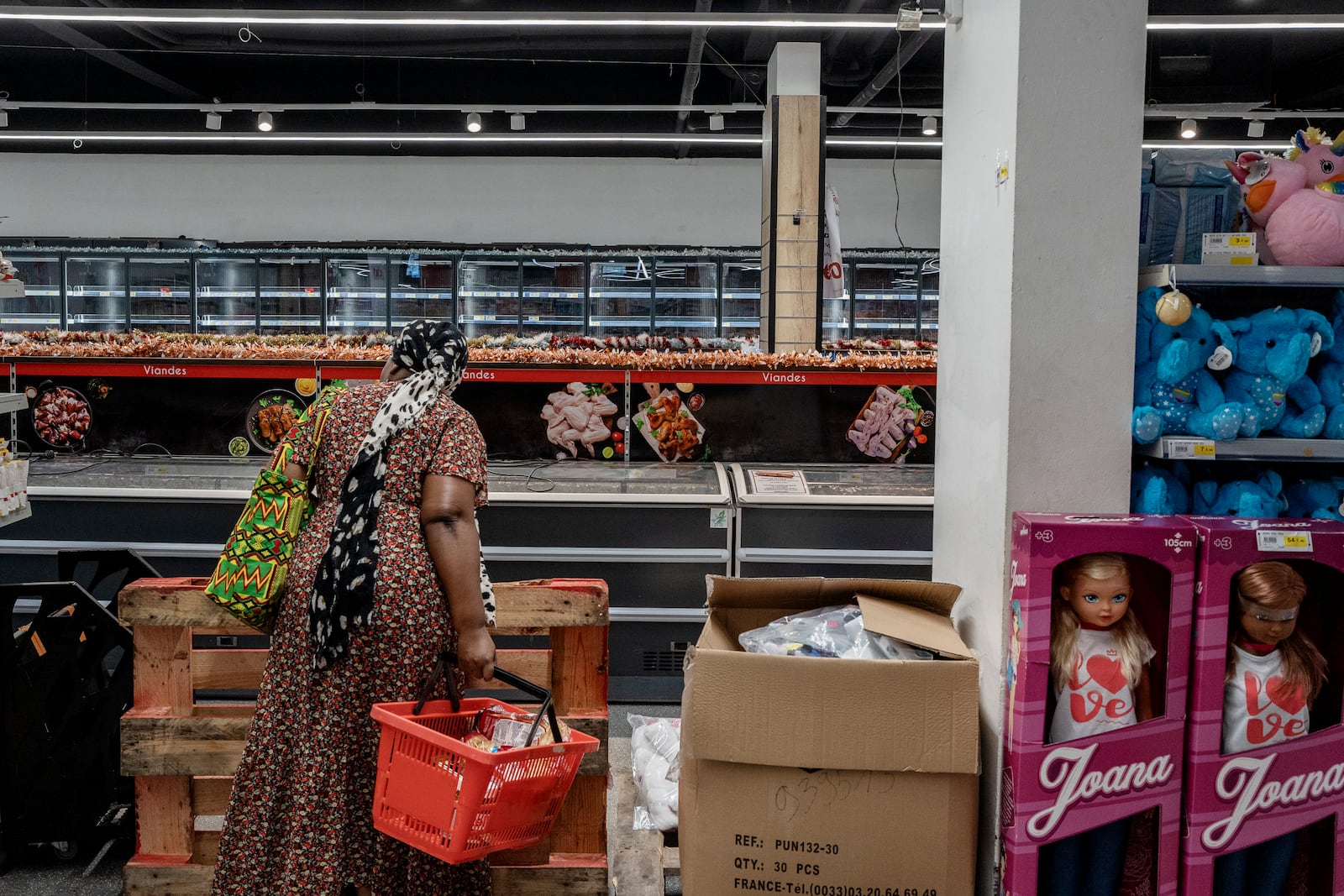 A woman looks at empty freezers as she looks for food supplies in Mamoudzou, Mayotte, Thursday, Dec. 19, 2024 (AP Photo/Adrienne Surprenant)