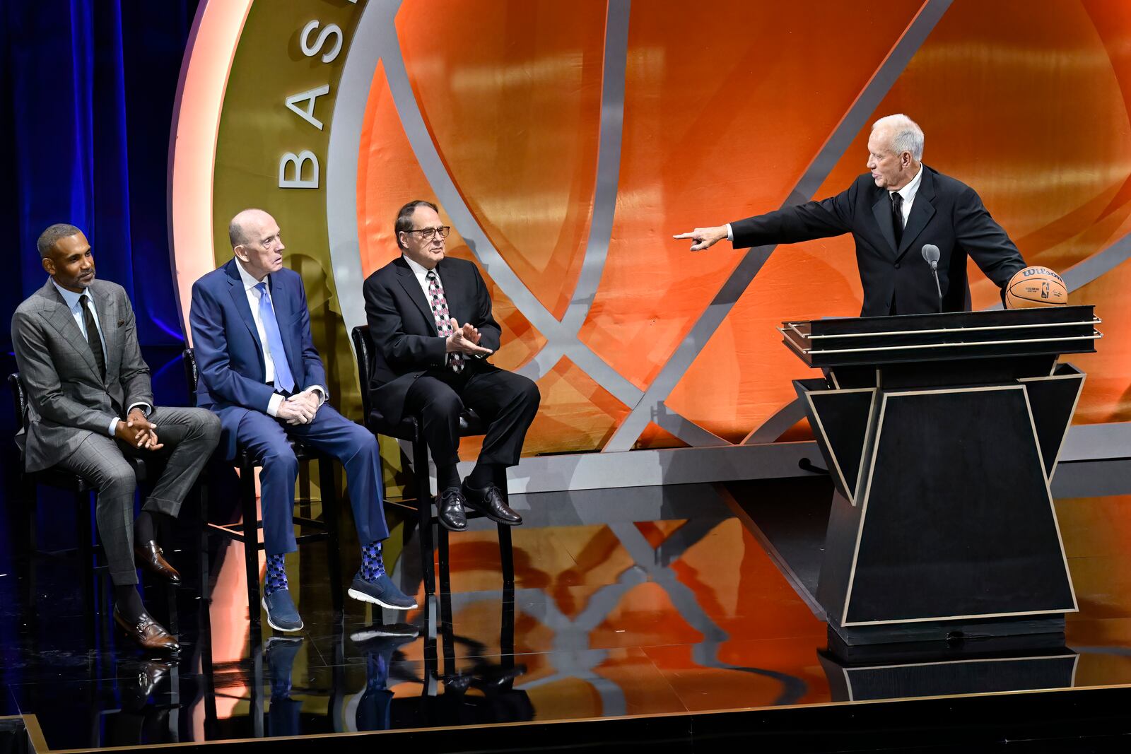 Doug Collins, right, points to his presenters, from left to right, Grant Hill, Billy Cunningham and Jerry Reinsdorf during his enshrinement in the Basketball Hall of Fame, Sunday Oct. 13, 2024, in Springfield, Mass. (AP Photo/Jessica Hill)