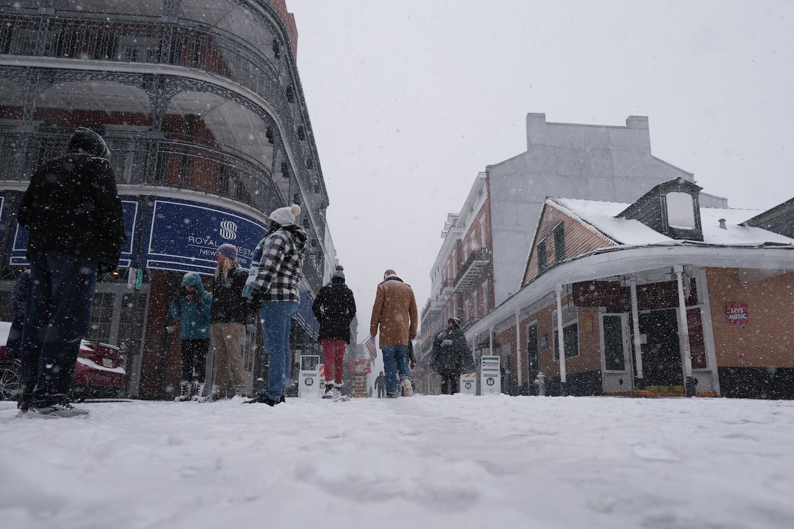 People walk in the French Quarter as snow falls in New Orleans, Tuesday, Jan. 21, 2025. (AP Photo/Gerald Herbert)