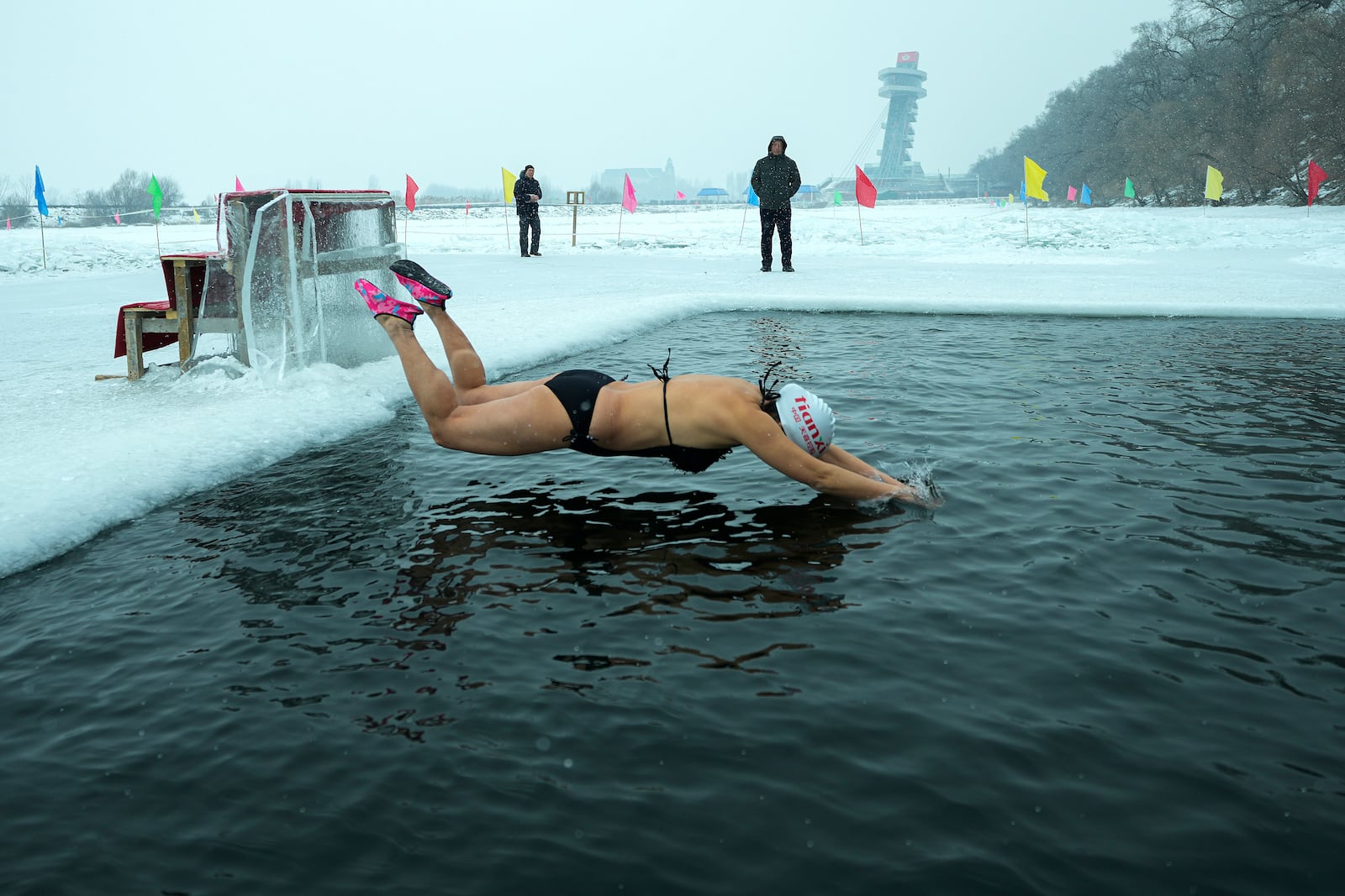 A woman jumps into a pool carved from ice on the frozen Songhua river in Harbin in northeastern China's Heilongjiang province, Tuesday, Jan. 7, 2025. (AP Photo/Andy Wong)