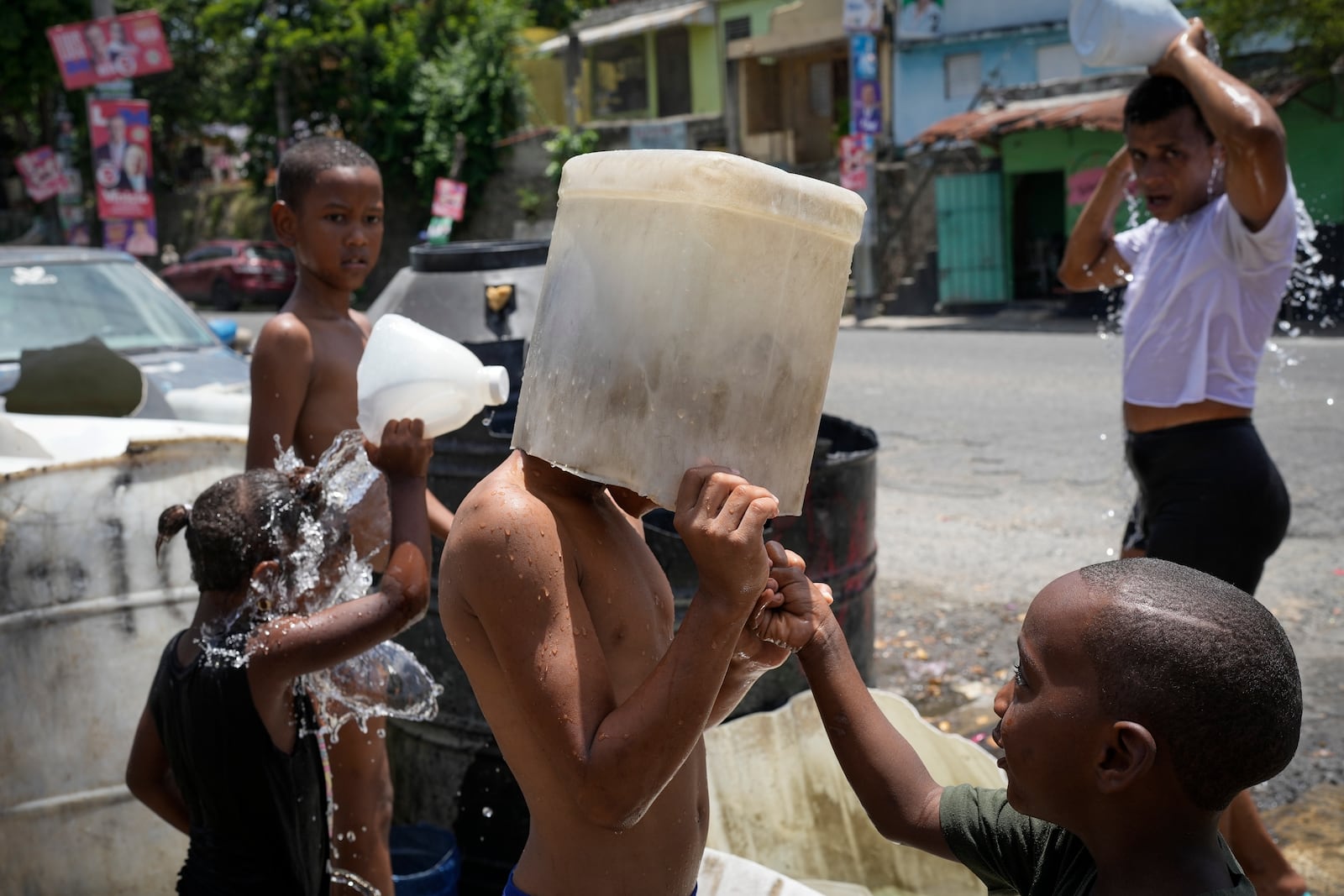 FILE - A child covers his head with a bucket on a hot day in the Los Guandules neighborhood of Santo Domingo, Dominican Republic, May 20, 2024. (AP Photo/Matias Delacroix, File)