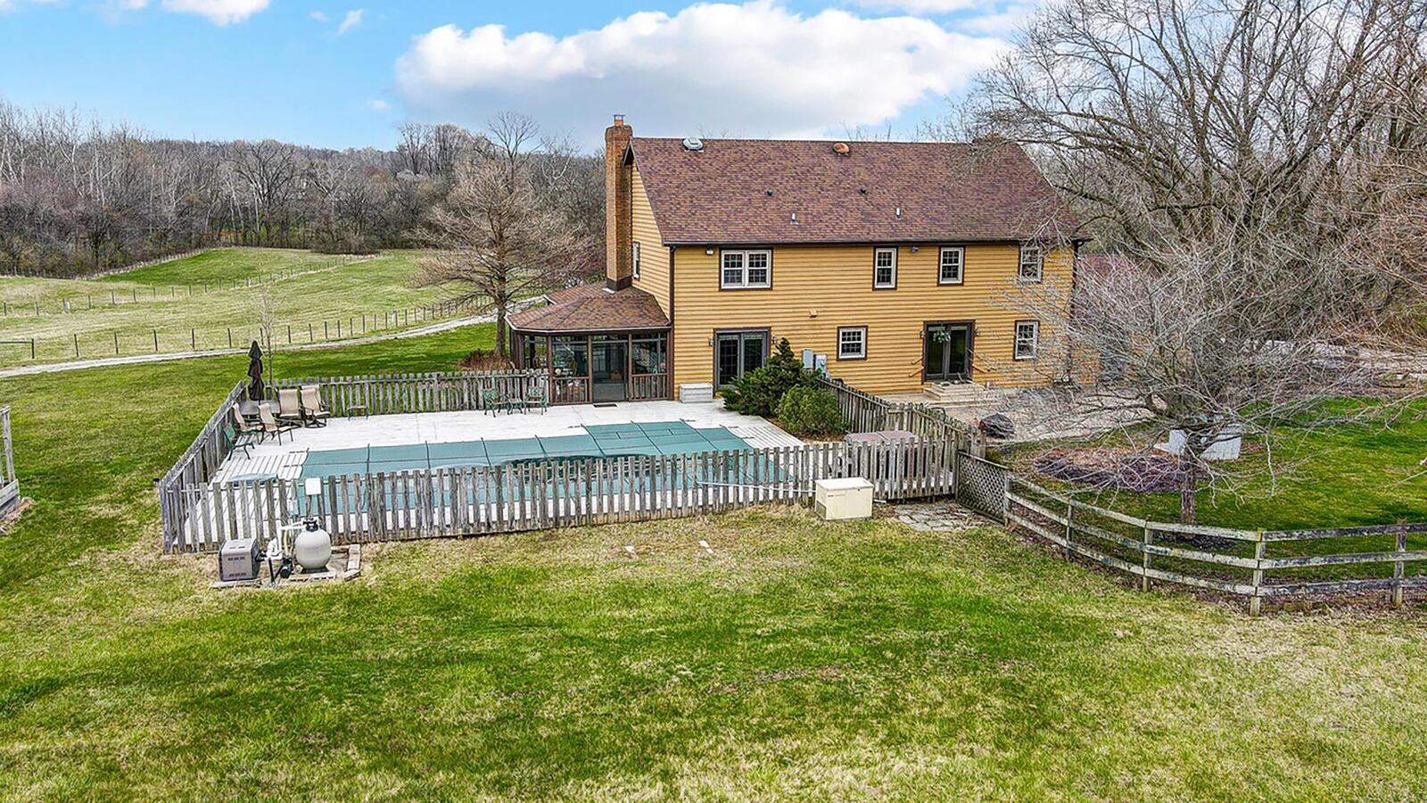 The rear of the home has an in-ground pool with a wood fence, paver patio and an additional wood fence surrounding the yard.