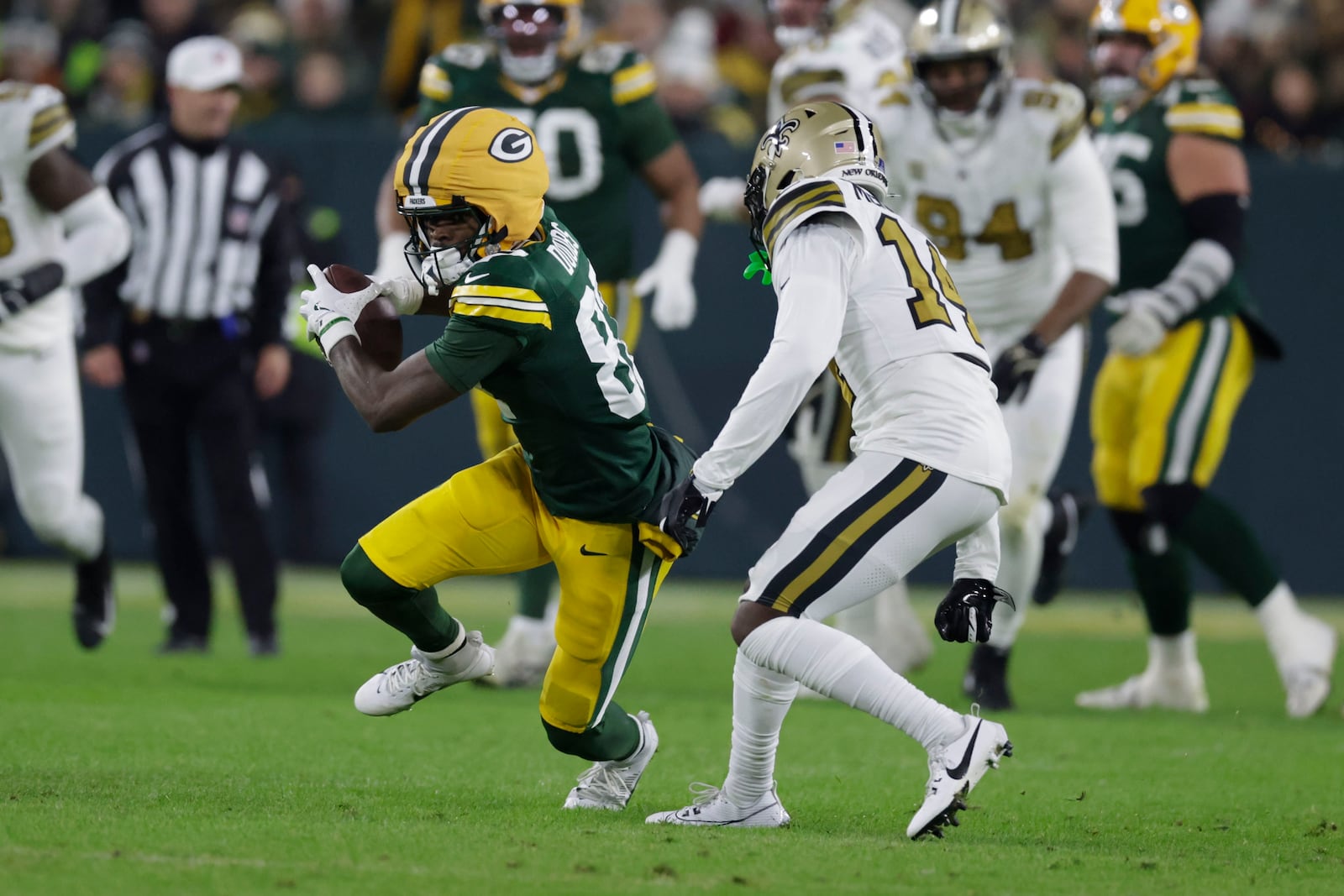 Green Bay Packers wide receiver Romeo Doubs (87) carries on a first down reception against New Orleans Saints cornerback Kool-Aid McKinstry (14) during the first half of an NFL football game, Monday, Dec. 23, 2024, in Green Bay, Wis. (AP Photo/Matt Ludtke)