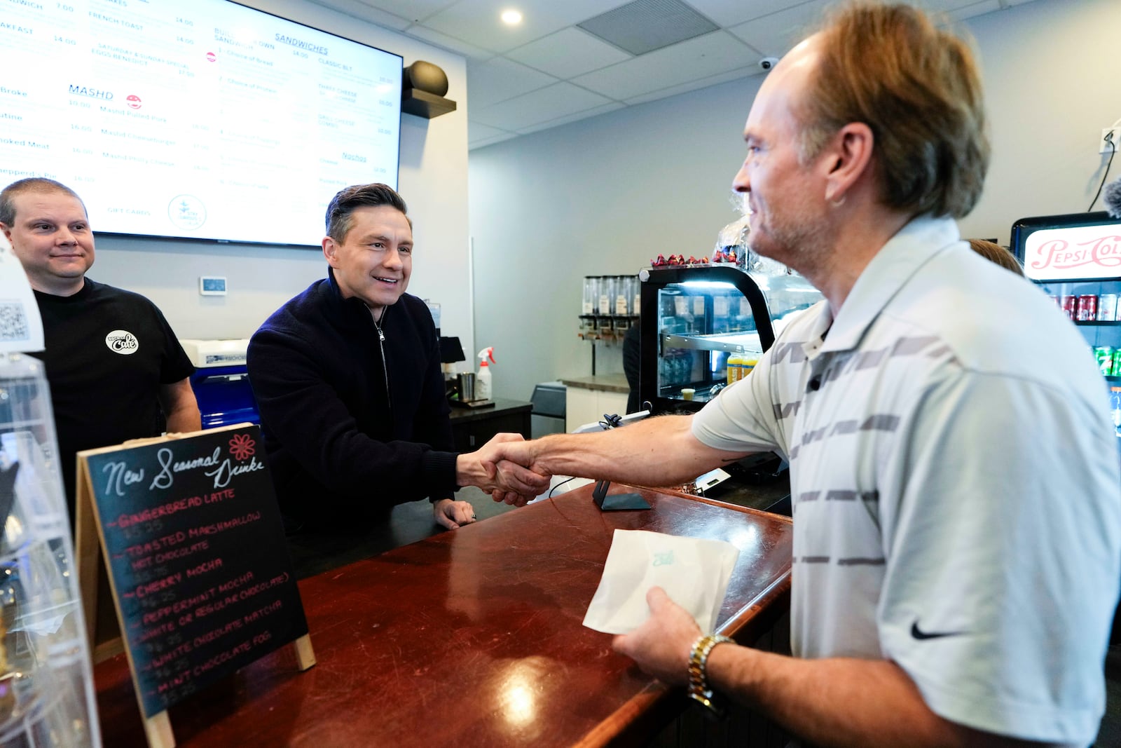 Conservative Leader Pierre Poilievre greets a supporter as he campaigns at a a cafe in the Orleans community of Ottawa, on Saturday, March 22, 2025. (Justin Tang /The Canadian Press via AP)