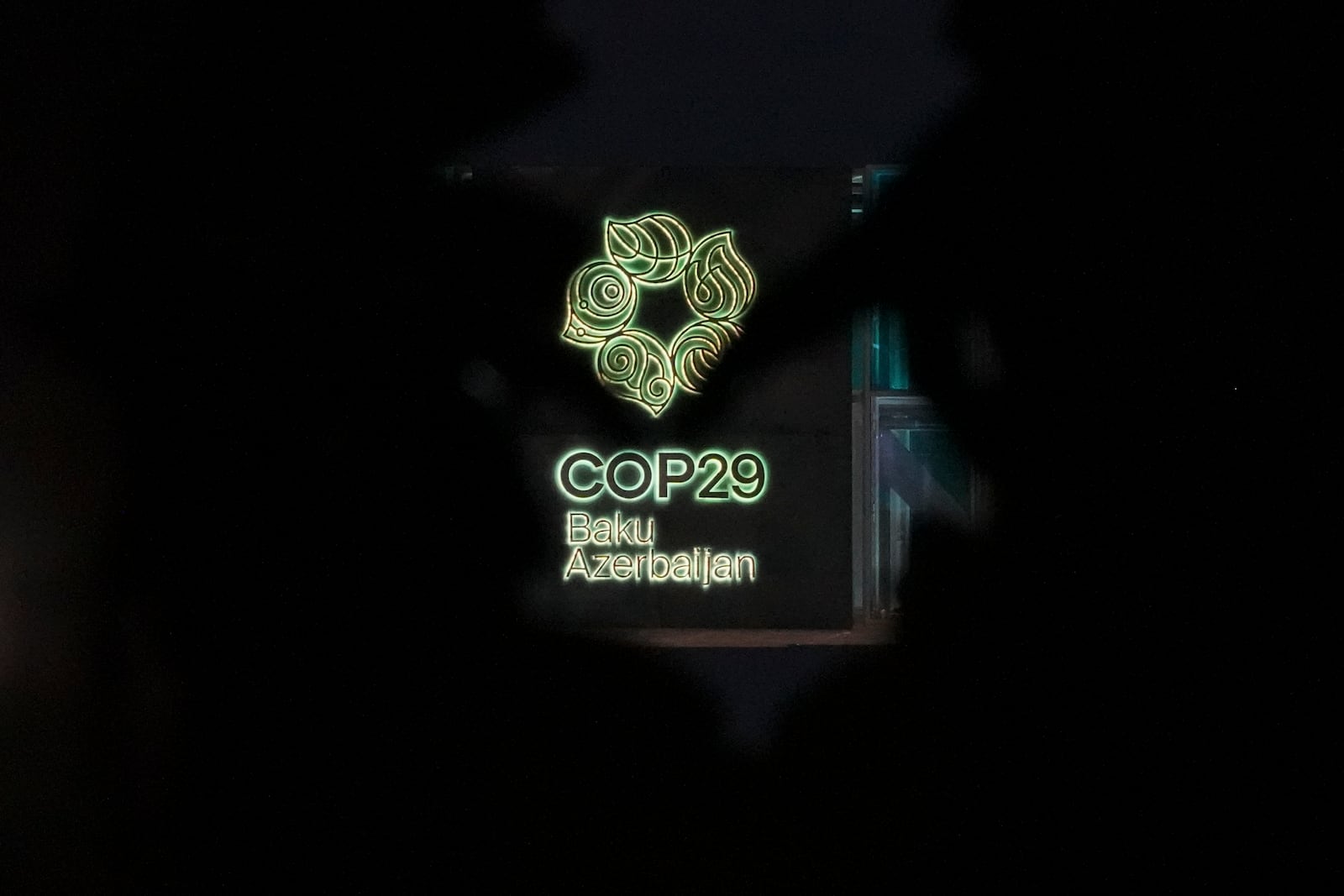 The logo for the COP29 U.N. Climate Summit is visible through artwork outside the venue, Tuesday, Nov. 12, 2024, in Baku, Azerbaijan. (AP Photo/Peter Dejong)