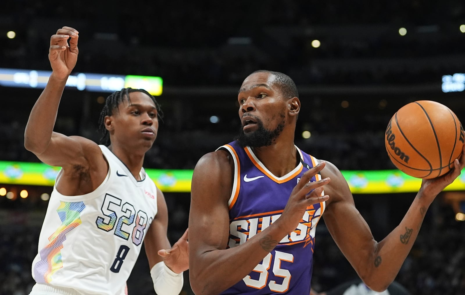 Phoenix Suns forward Kevin Durant, right, looks to pass the ball as Denver Nuggets forward Peyton Watson defends in the second half of an NBA basketball game Monday, Dec. 23, 2024, in Denver. (AP Photo/David Zalubowski)