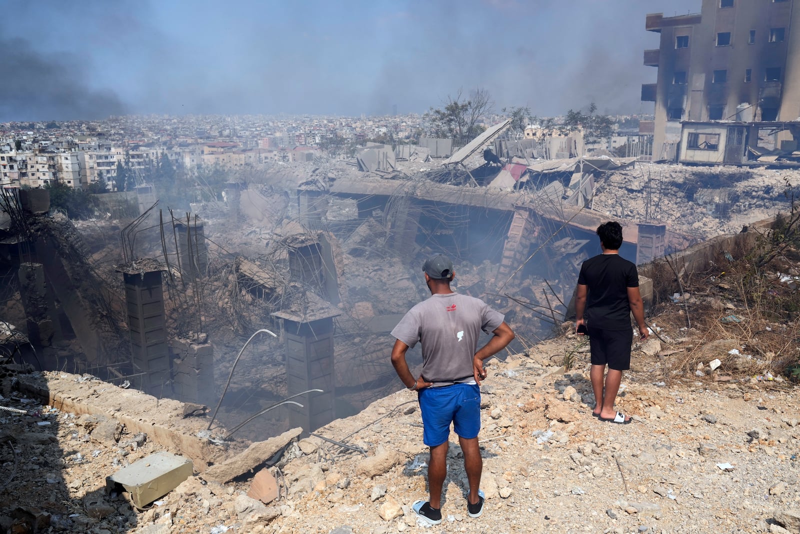 FILE - People check a damaged building at the site of an Israeli airstrike in Choueifat, south east of Beirut, on Sept. 28, 2024. (AP Photo/Hussein Malla, File)