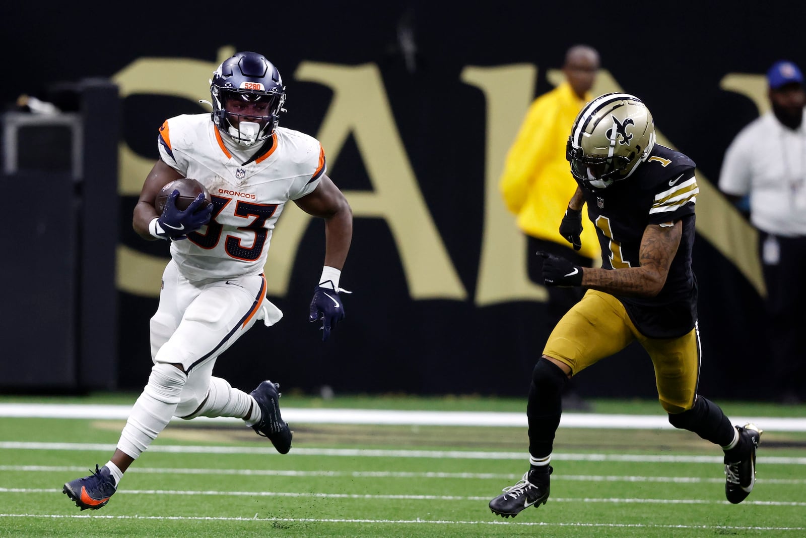 Denver Broncos running back Javonte Williams (33) runs from New Orleans Saints cornerback Alontae Taylor (1) during the second half of an NFL football game, Thursday, Oct. 17, 2024, in New Orleans. (AP Photo/Butch Dill)