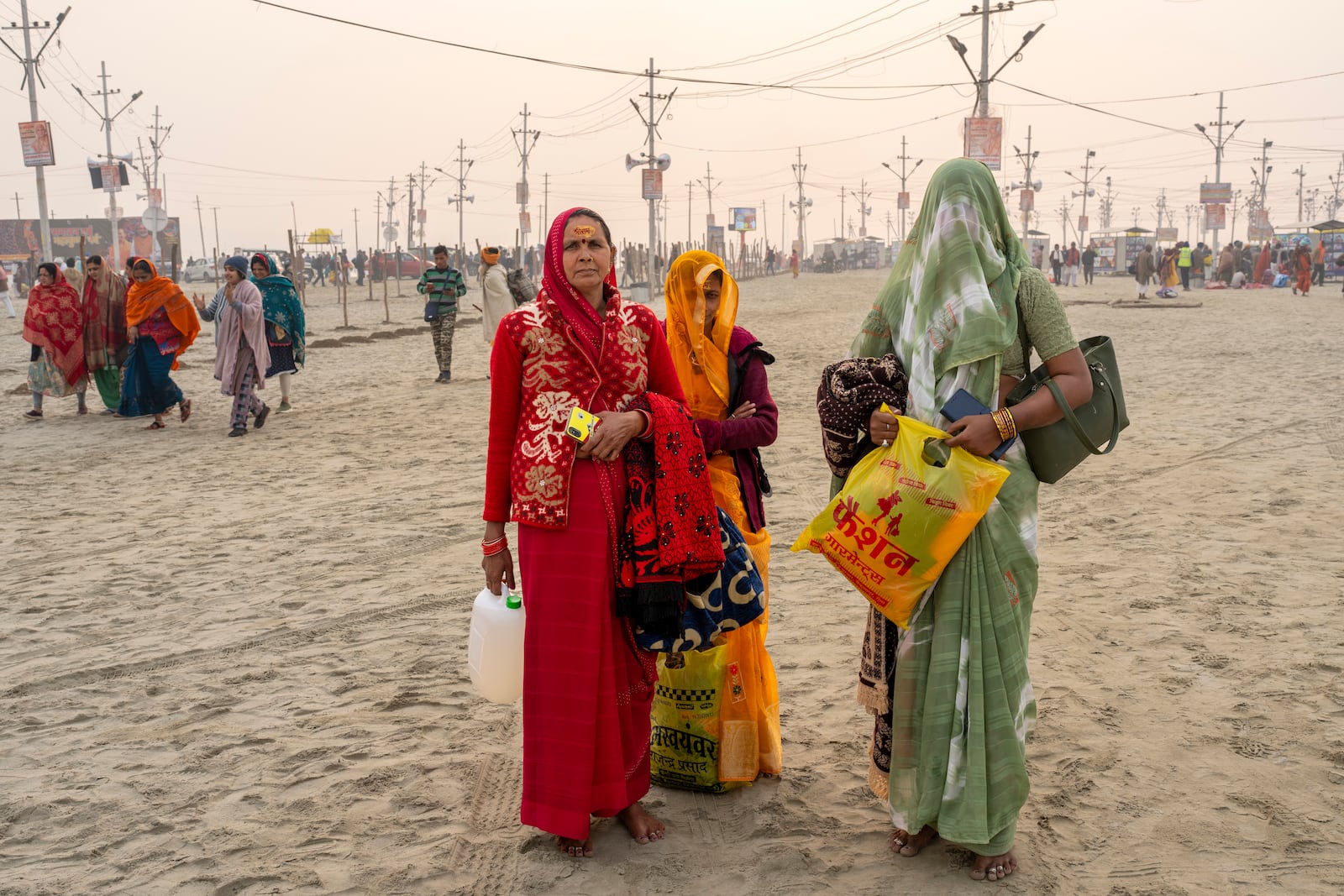 Hindu women wait to join their family members after bathing at the confluence of the Ganges, the Yamuna and the mythical Saraswati rivers, a day before the official beginning of the 45-day-long Maha Kumbh festival, in Prayagraj, India, Sunday, Jan. 12, 2025. (AP Photo/Ashwini Bhatia)