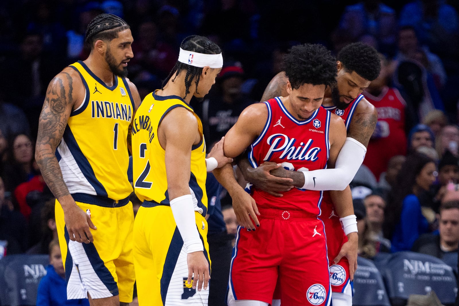 Philadelphia 76ers' Jared McCain, center right, gets helped by Paul George, right, and Indiana Pacers' Andrew Nembhard, center left, after a hard fall to the court during the second half of an NBA basketball game, Friday, Dec. 13, 2024, in Philadelphia. The Pacers won 121-107. (AP Photo/Chris Szagola)