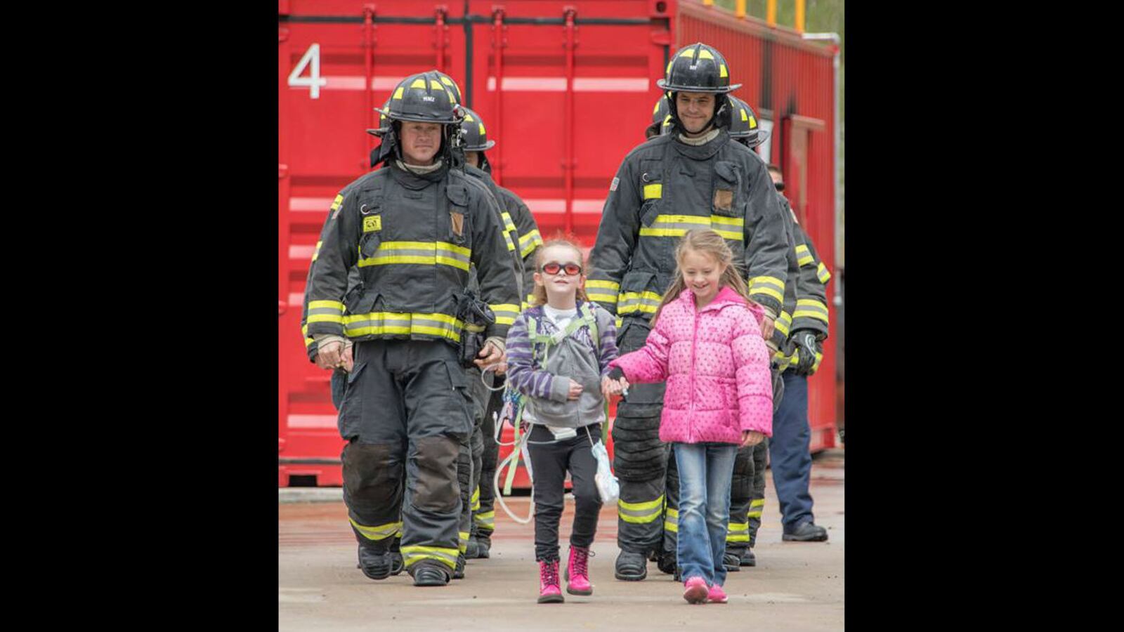 Olivia Gant, center, walks with firefighters in an April 2017 photo. Olivia's mother, Kelly Turner, is accused of murder, fraud and other charges in her Aug. 20, 2017, death. Authorities say Turner, 41, lied about her daughter being terminally ill.