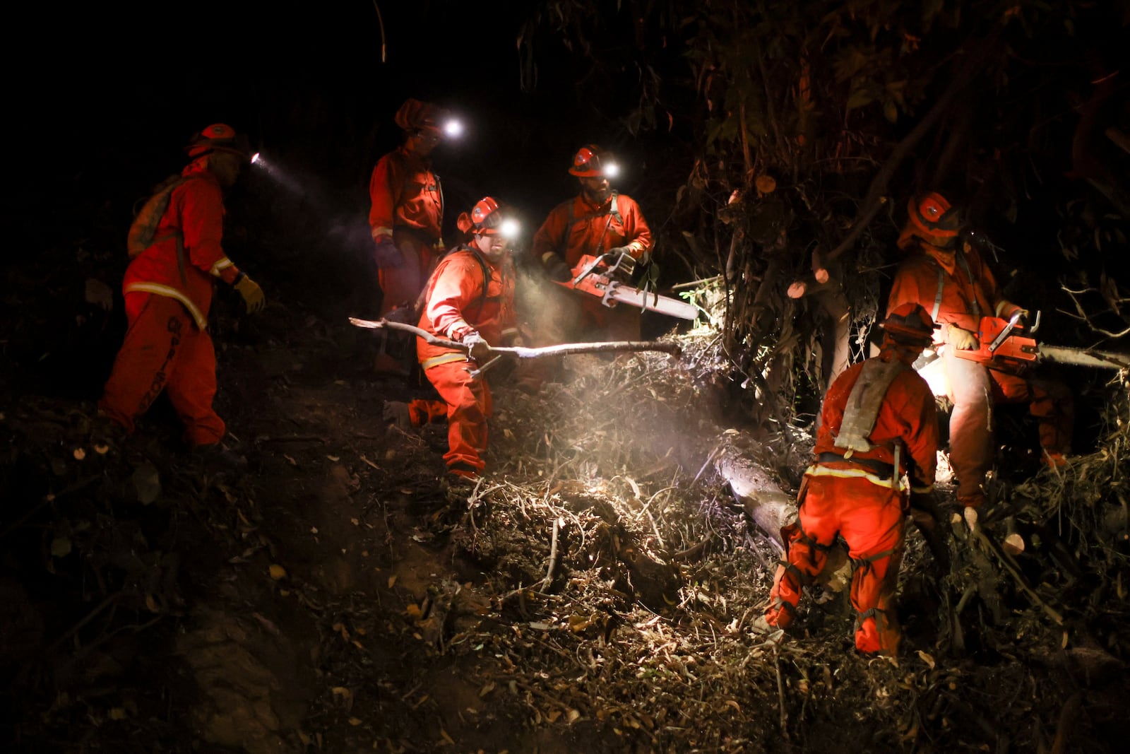 FILE - A California Department of Corrections hand crew works containment lines ahead of the Palisades Fire, Jan. 14, 2025, in Santa Monica, Calif. (AP Photo/Ethan Swope, File)