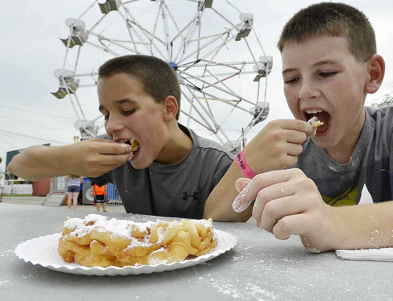 Two boys enjoy a hot funnel cake on the midway at a previous Clark County Fair Friday. Bill Lackey/Staff