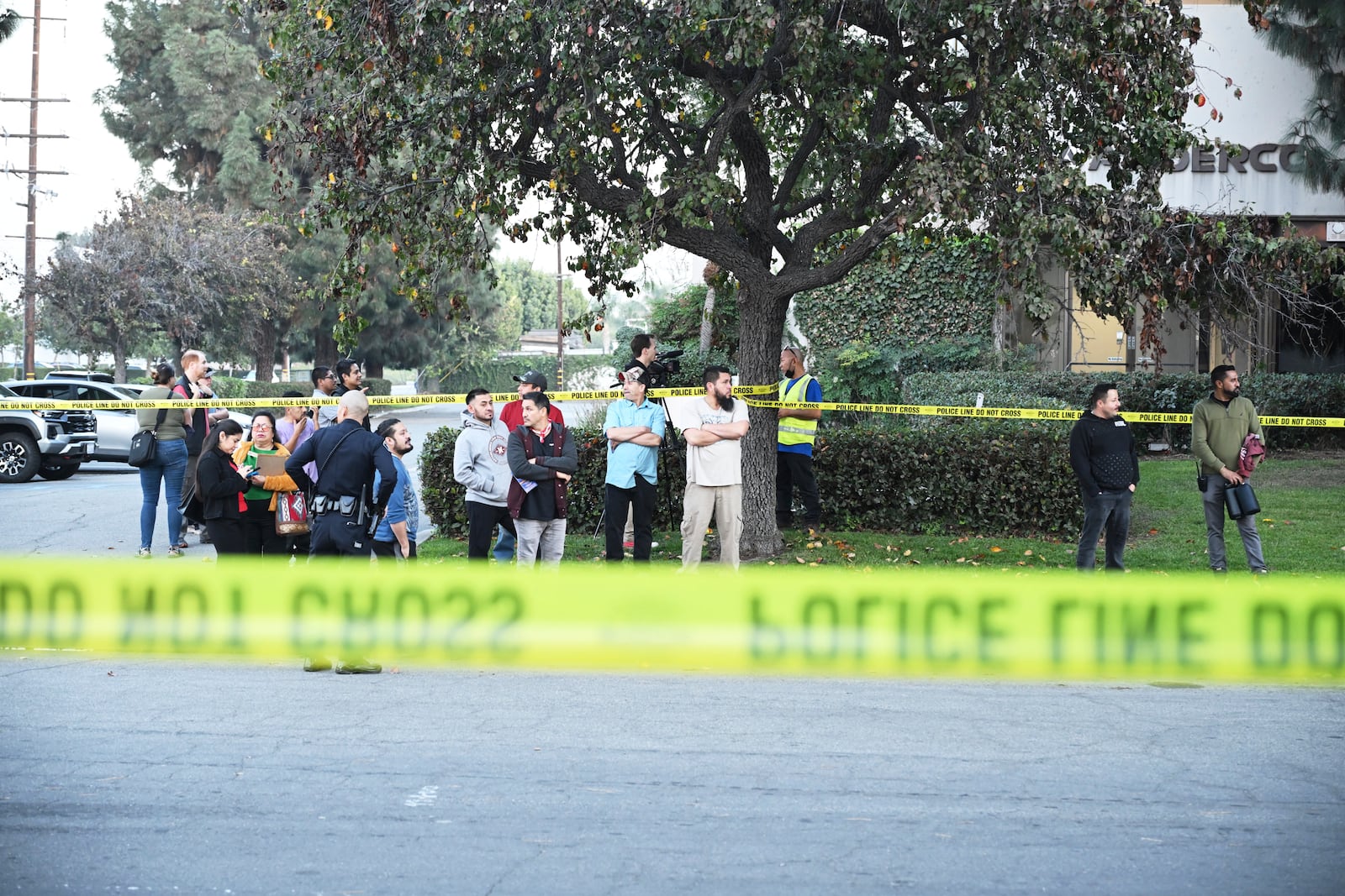 Workers stand near police lines at the scene of a small plane crash, Thursday, Jan. 2, 2025, in Fullerton, Calif. (AP Photo/Kyusung Gong)