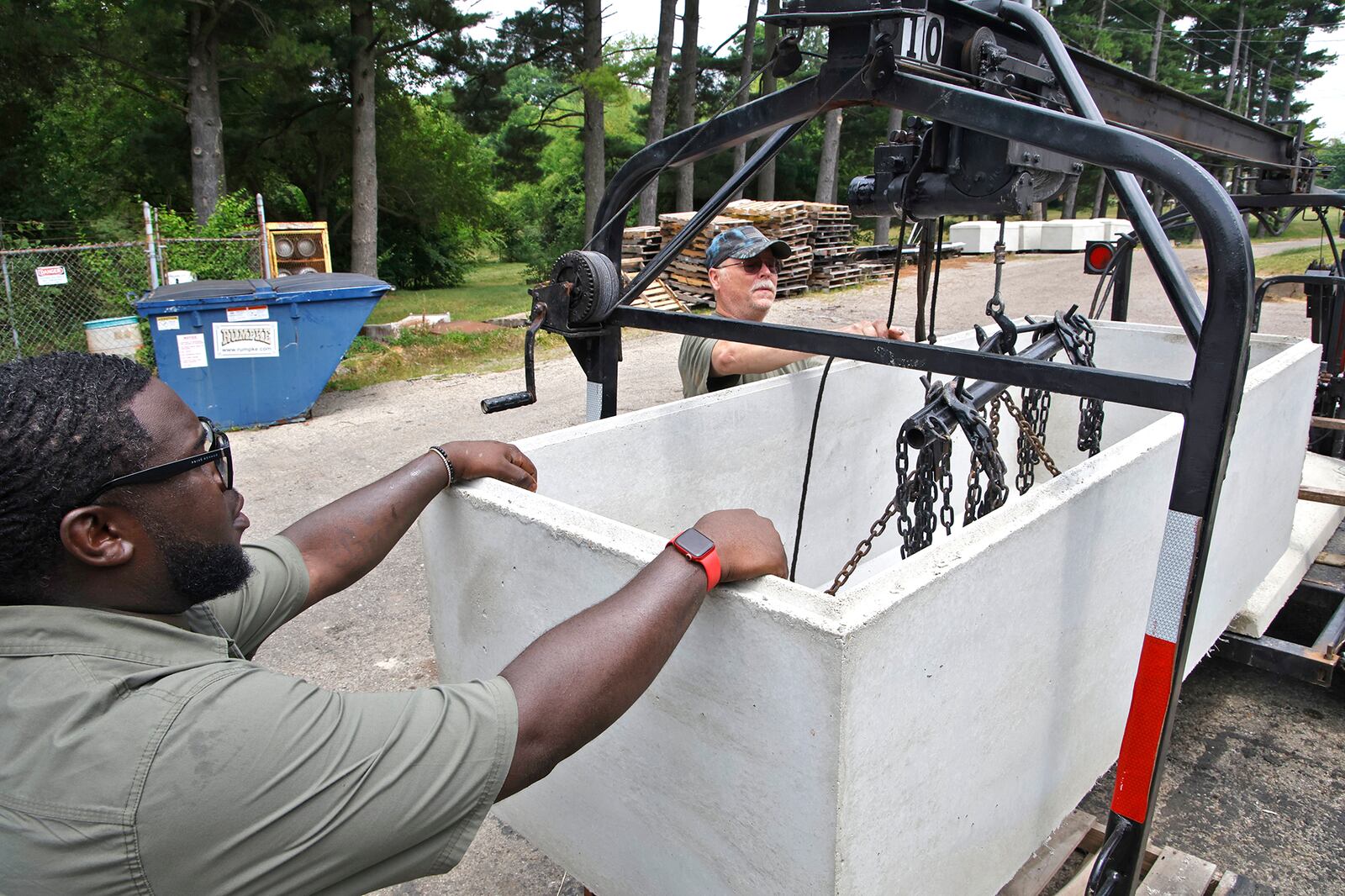 Quan Wade, left, and Frank Hamilton load a vault on a trailer Wednesday, June 19, 2024 at The Springfield Vault Company on St. Paris Pike. BILL LACKEY/STAFF