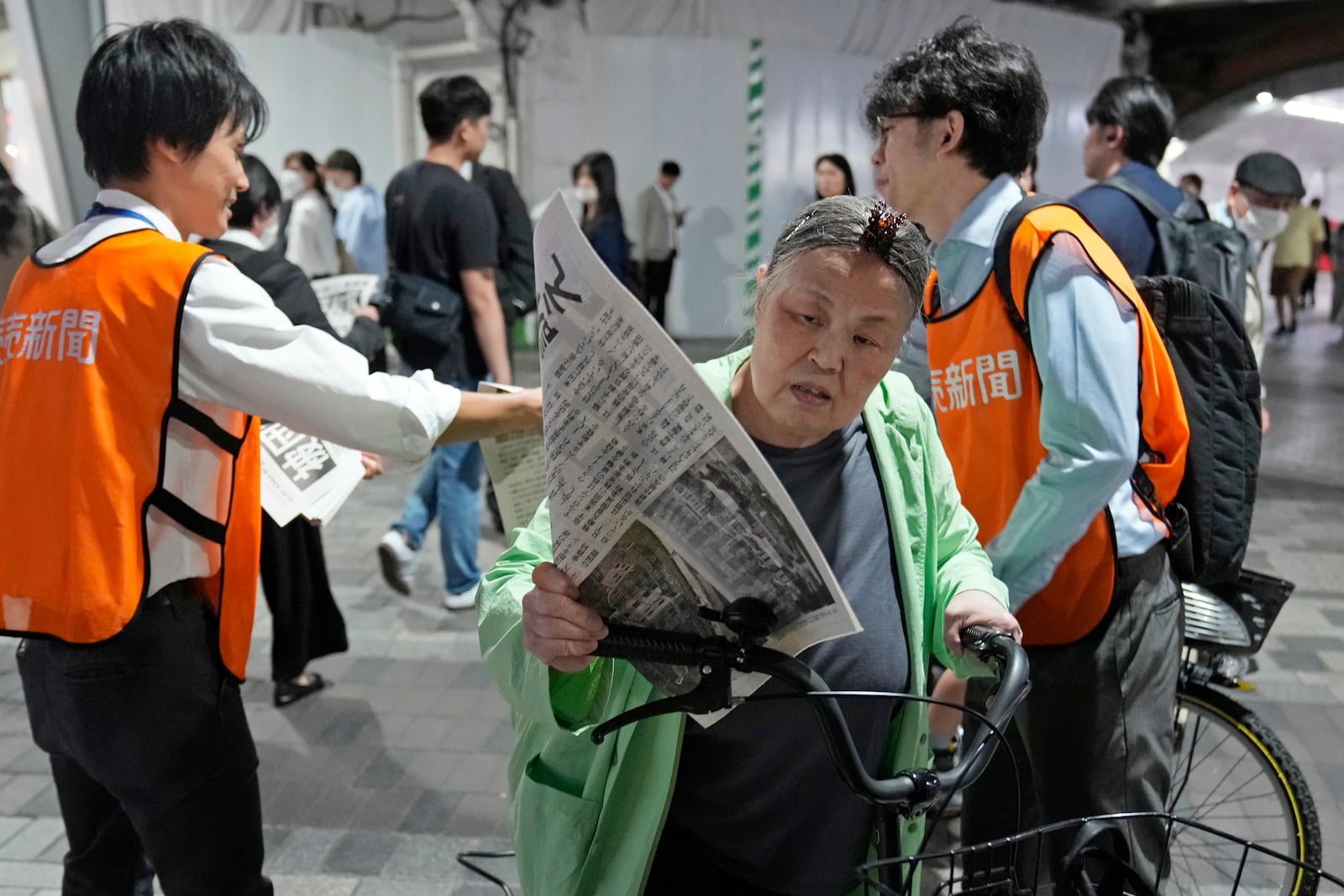 A person reads a copy of an extra version as workers of the Yomiuri Shimbun newspaper hand out its copies to passersby in Tokyo, Friday, Oct. 11, 2024, after Nihon Hidankyo, or the Japan Confederation of A- and H-Bomb Sufferers Organizations, won the Nobel Peace Prize. (AP Photo/Shuji Kajiyama)