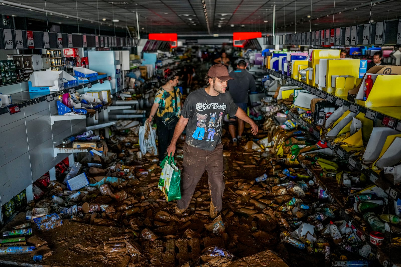 People pick up goods in a supermarket affected by the floods in Valencia, Spain, Thursday, Oct. 31, 2024. (AP Photo/Manu Fernandez)