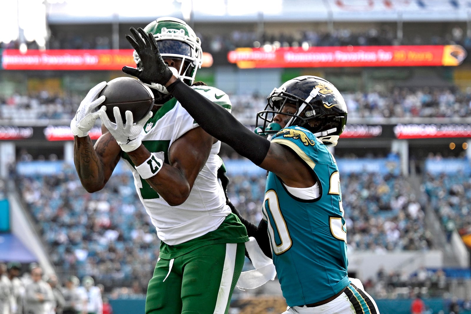 New York Jets wide receiver Davante Adams (17) catches a 1-yard touchdown pass in front of Jacksonville Jaguars cornerback Montaric Brown (30) during the second half of an NFL football game Sunday, Dec. 15, 2024, in Jacksonville, Fla. (AP Photo/Phelan M. Ebenhack)