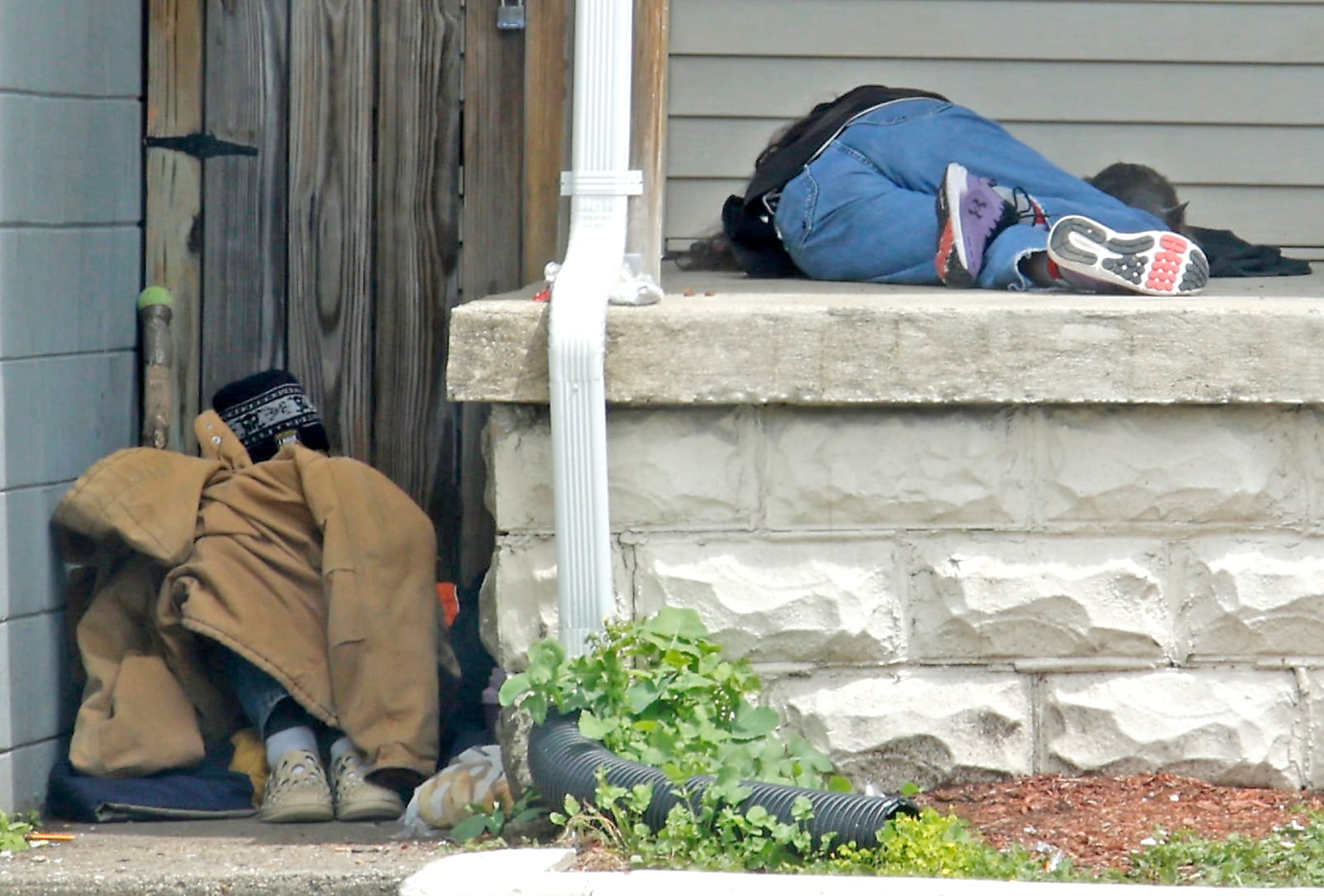 Several men sleep on the front porch of the Shelter Inc. men's homeless shelter when the shelter, located along West High Street, closes during the day. BILL LACKEY/STAFF