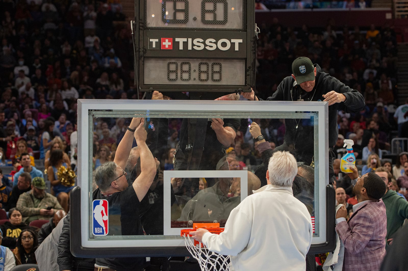 Workers try to repair a defective backboard and basket before an NBA basketball game between the Cleveland Cavaliers and the Utah Jazz in Cleveland, Monday, Dec. 23, 2024. The game was delayed for the repair. (AP Photo/Phil Long)