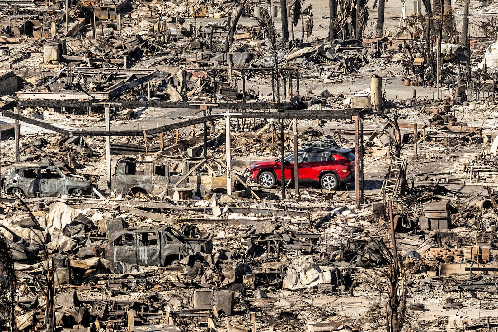 A car drives past homes and vehicles destroyed by the Palisades Fire at the Pacific Palisades Bowl Mobile Estates on Jan. 12, 2025, in Los Angeles. (AP Photo/Noah Berger)