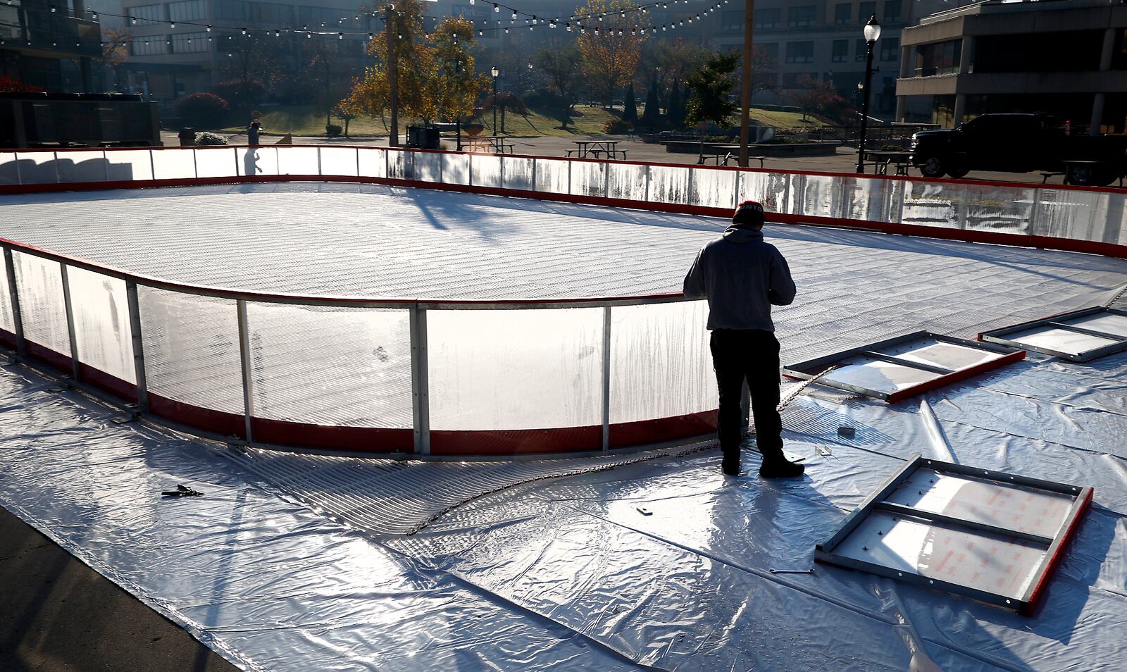 The new ice skating rink being constructed on the Springfield City Hall Plaza glows in the morning sunlight as a worker erects the transparent wall around the outside Thursday, Nov. 3, 2022. Precision Ice Rinks is the company building the ice rink that will open Nov. 25 for the Holiday in the City celebration and continue through New Year's Eve. BILL LACKEY/STAFF