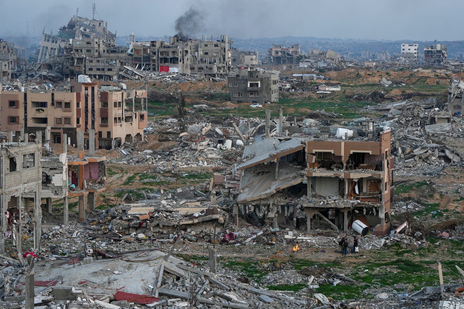 Palestinians stand next to a fire beside a destroyed house in an area littered with rubble from buildings destroyed during the Israeli army's ground and air offensive against Hamas, in Gaza City, Tuesday Feb. 4, 2025.(AP Photo/Abdel Kareem Hana)