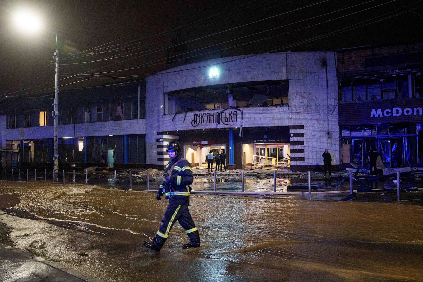 A rescue worker crosses a flooded street after a Russian missile strike on Kyiv, Ukraine, Saturday, Jan. 18, 2024. (AP Photo/Evgeniy Maloletka)